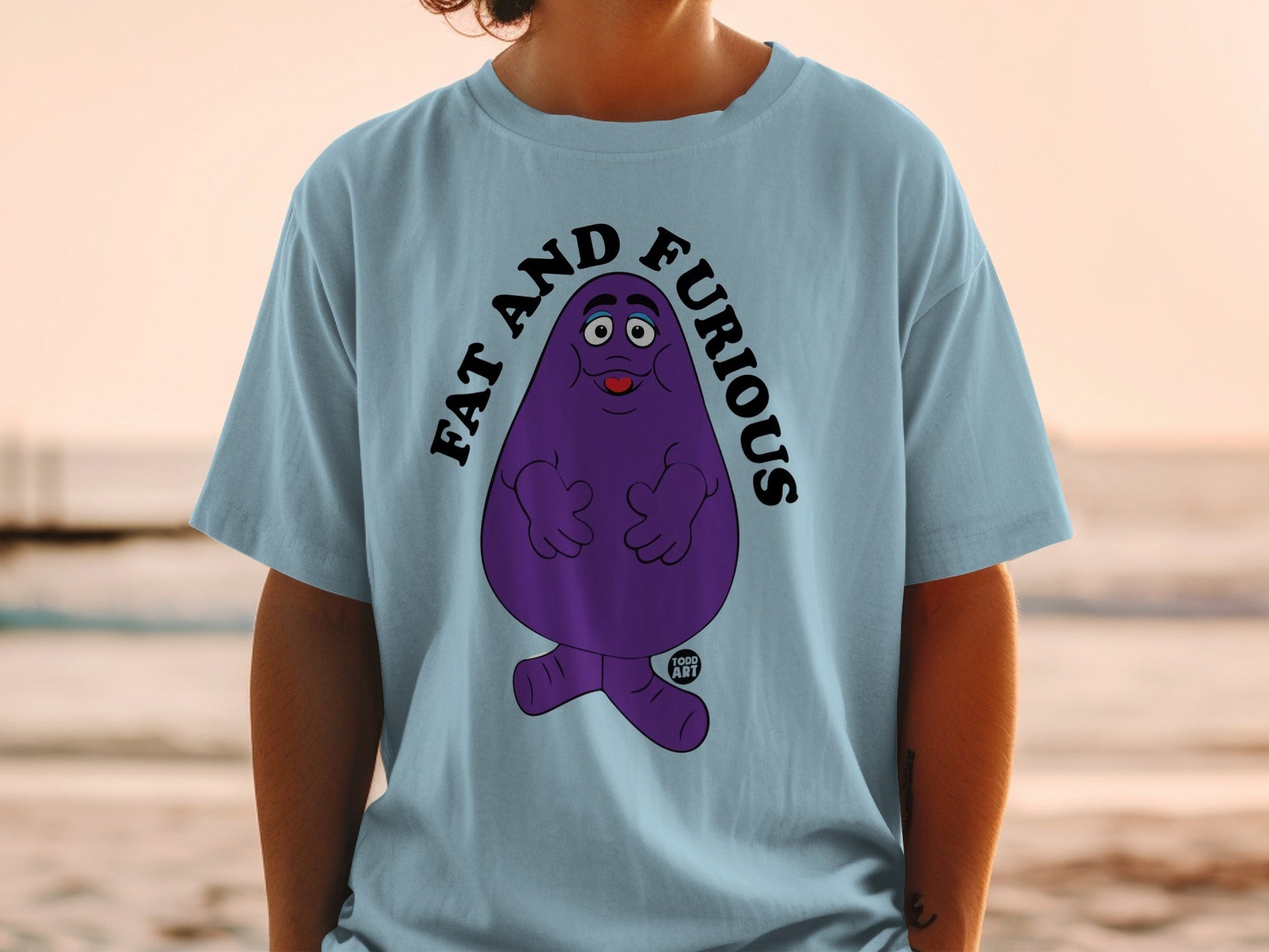 Light blue t-shirt with a cartoon purple character and "FAT AND FURIOUS" text.