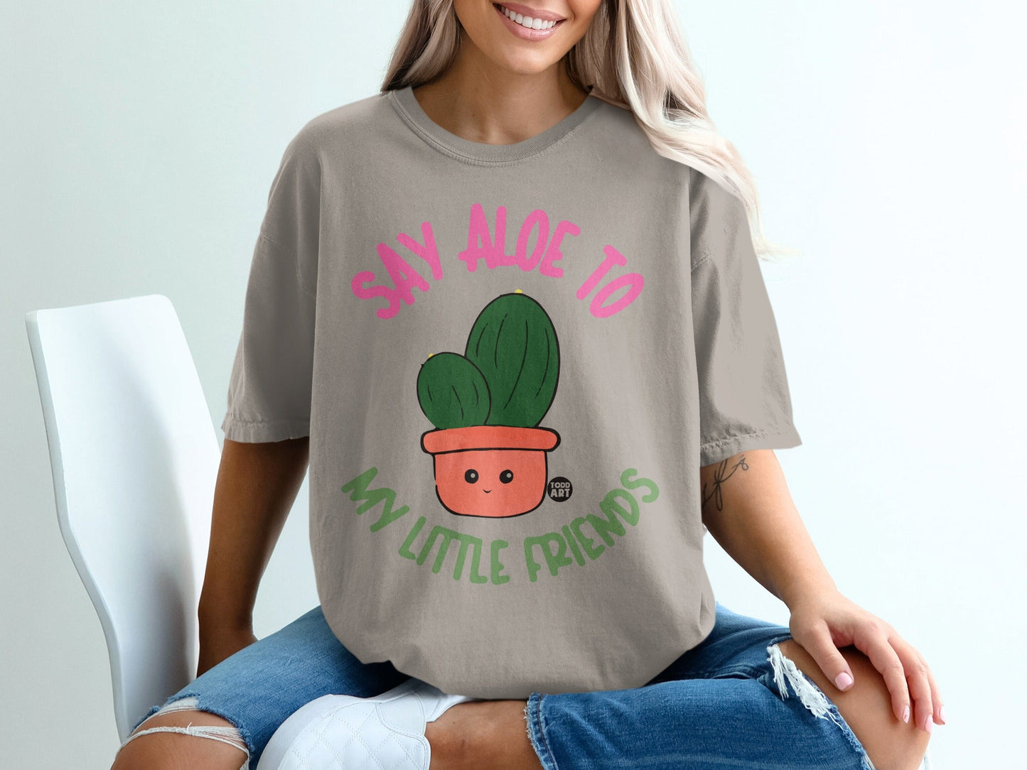 T-shirt with pink text "SAY ALOE TO MY LITTLE FRIENDS" and cartoon cactus.