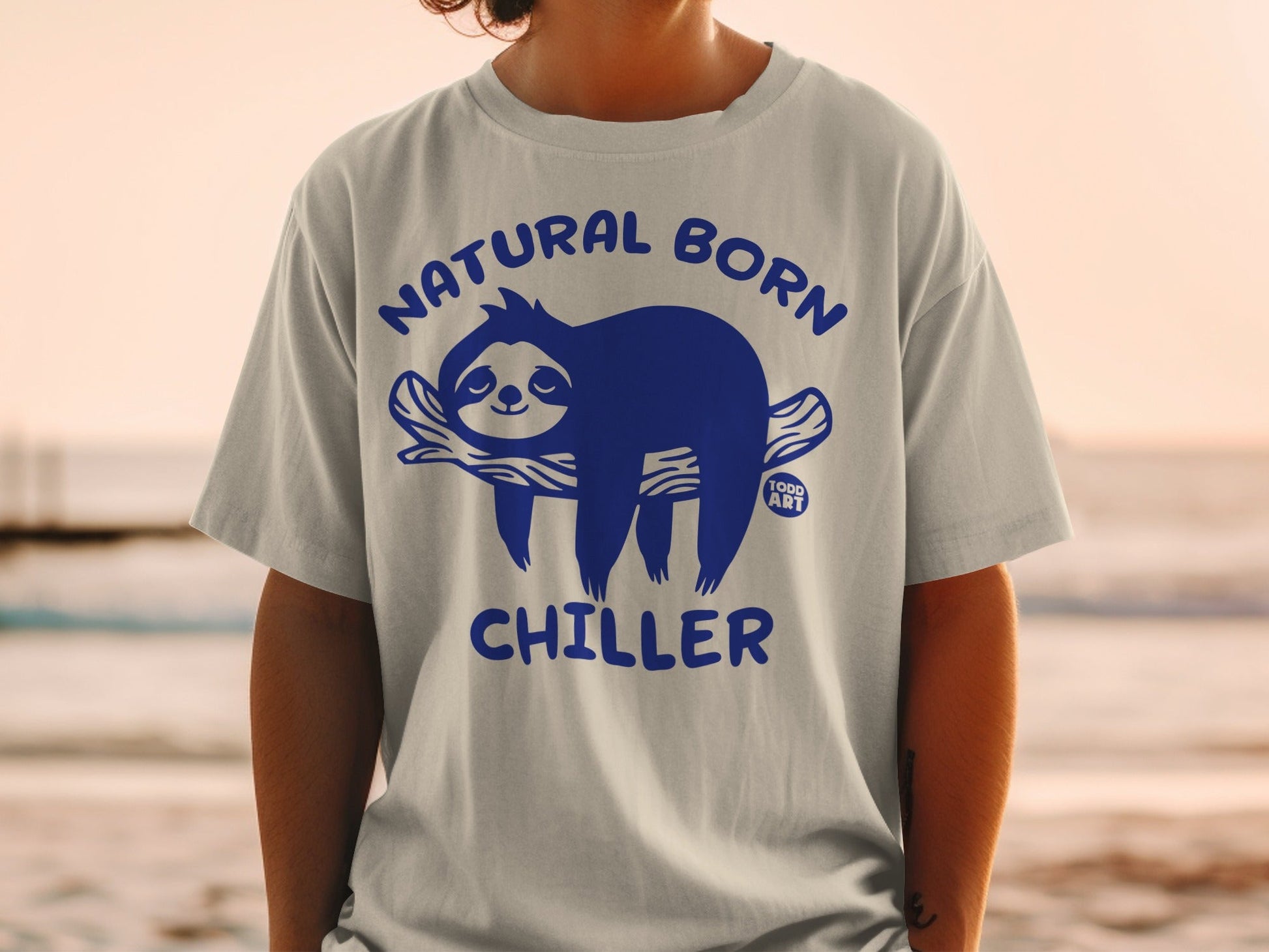 Light gray t-shirt with blue sloth graphic and text "NATURAL BORN CHILLER".