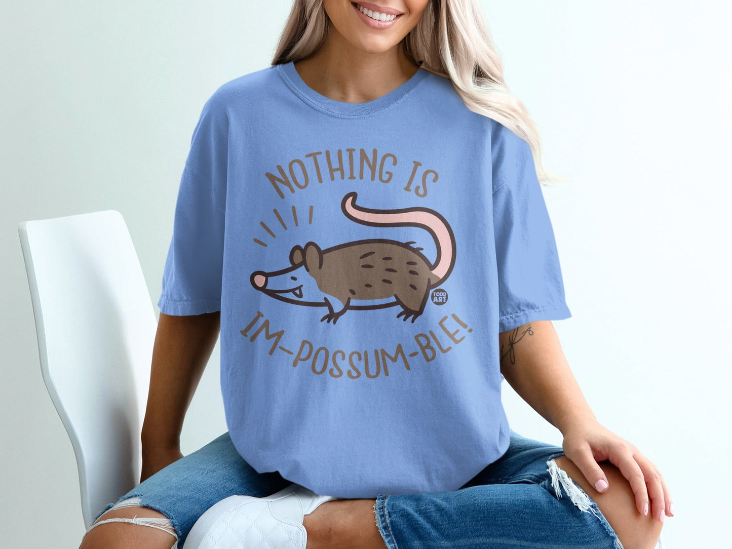 Light blue t-shirt with a cartoon possum and the text "NOTHING IS IM-POSSUM-BLE!".