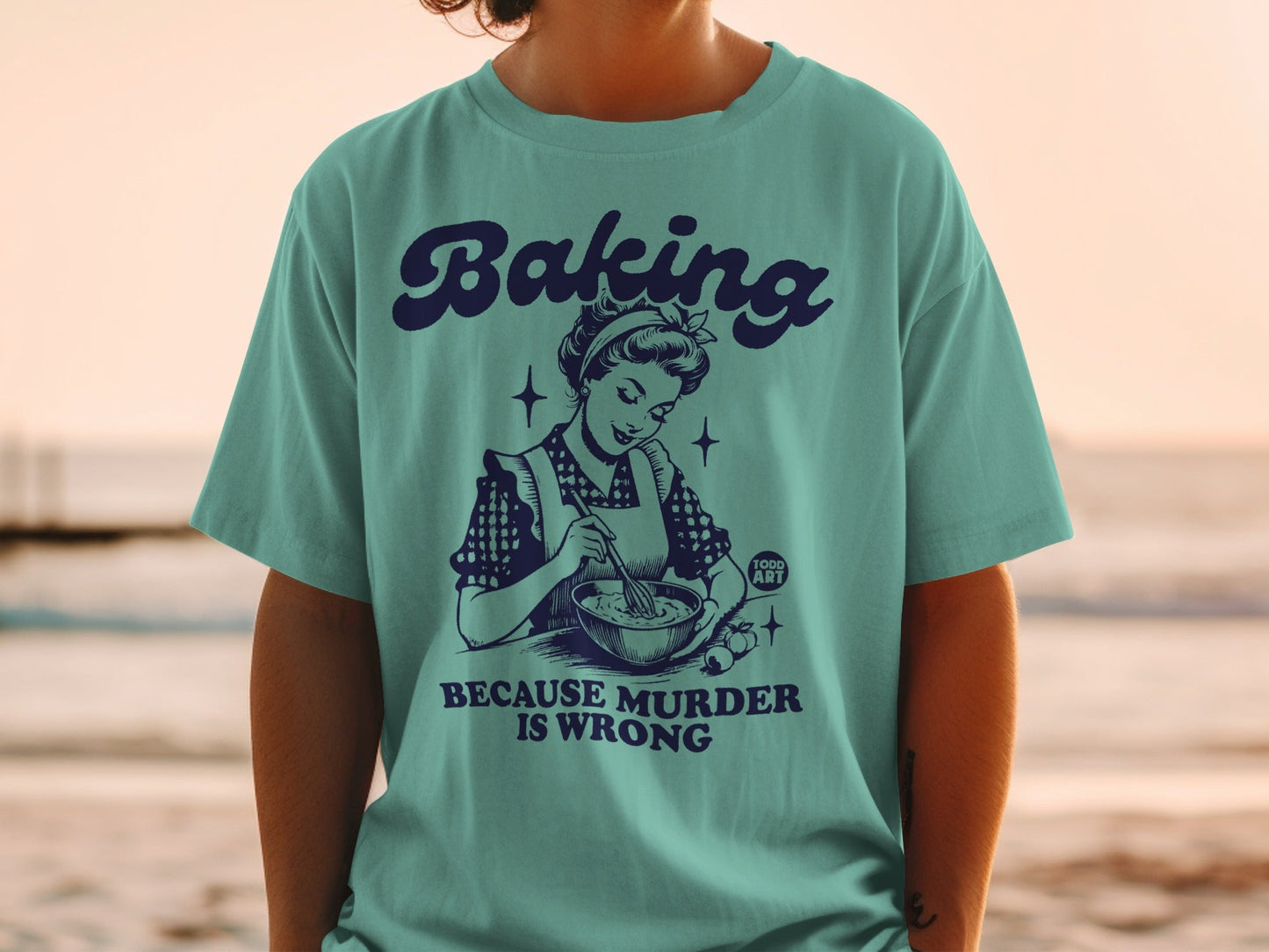 Teal t-shirt with retro illustration and text "Baking is wrong".