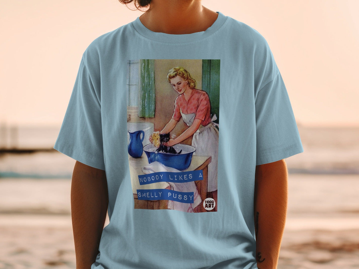 Woman in apron washes cat in sink, text "NOBODY LIKES A SMELLY PUSSY".