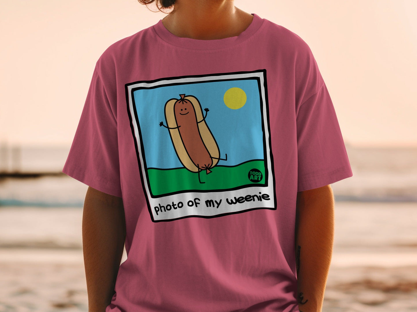 Cartoon hot dog with arms raised on grass, "photo of my weenie" text.