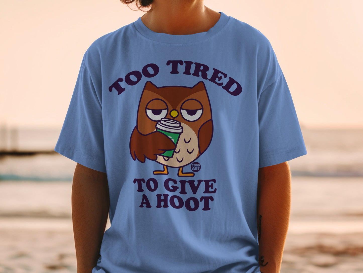 Blue t-shirt with cartoon owl holding coffee cup and text "TOO TIRED TO GIVE A HOOT".
