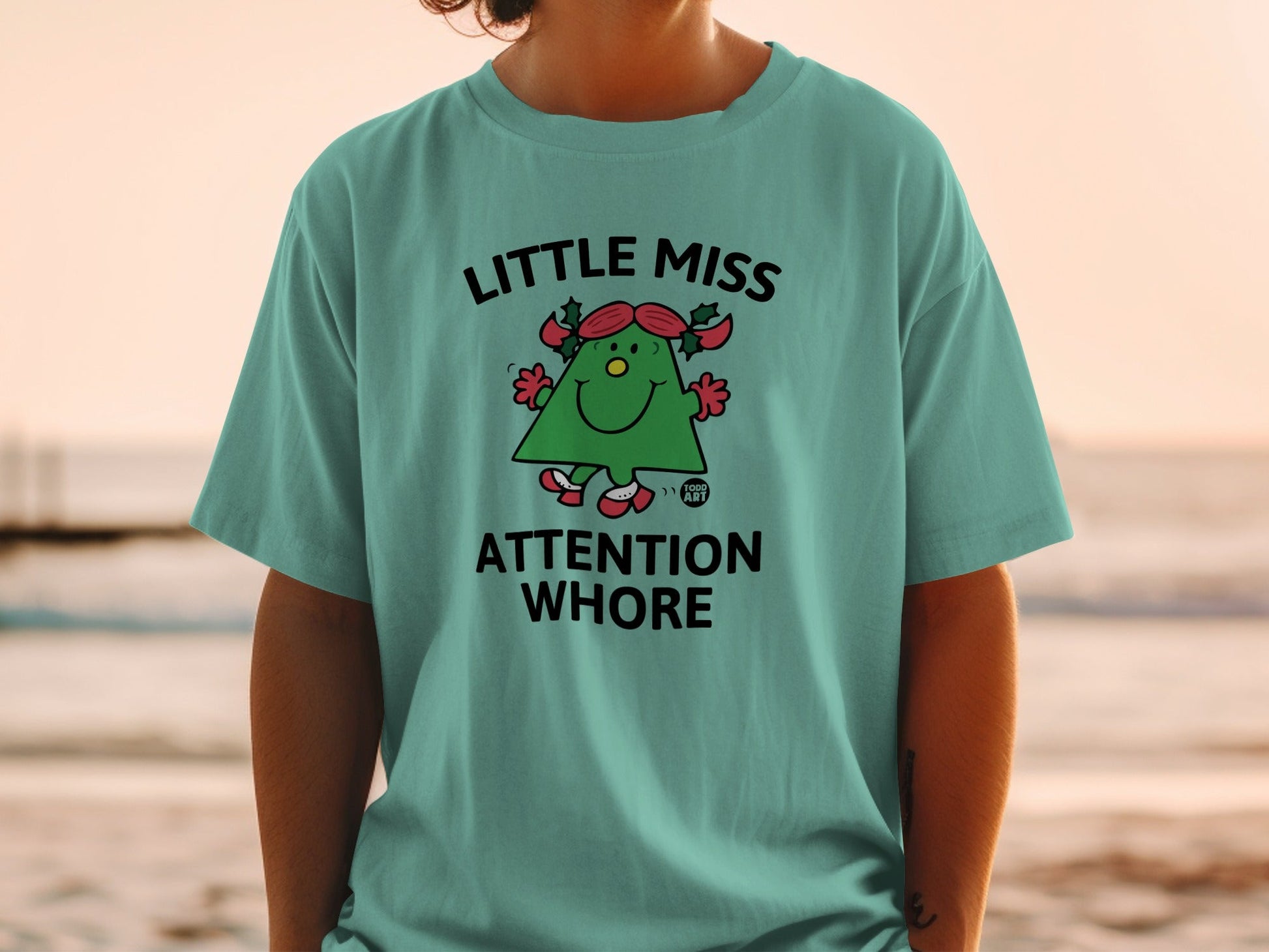 Green t-shirt with cartoon Christmas tree, "Little Miss Attention Whore" text.