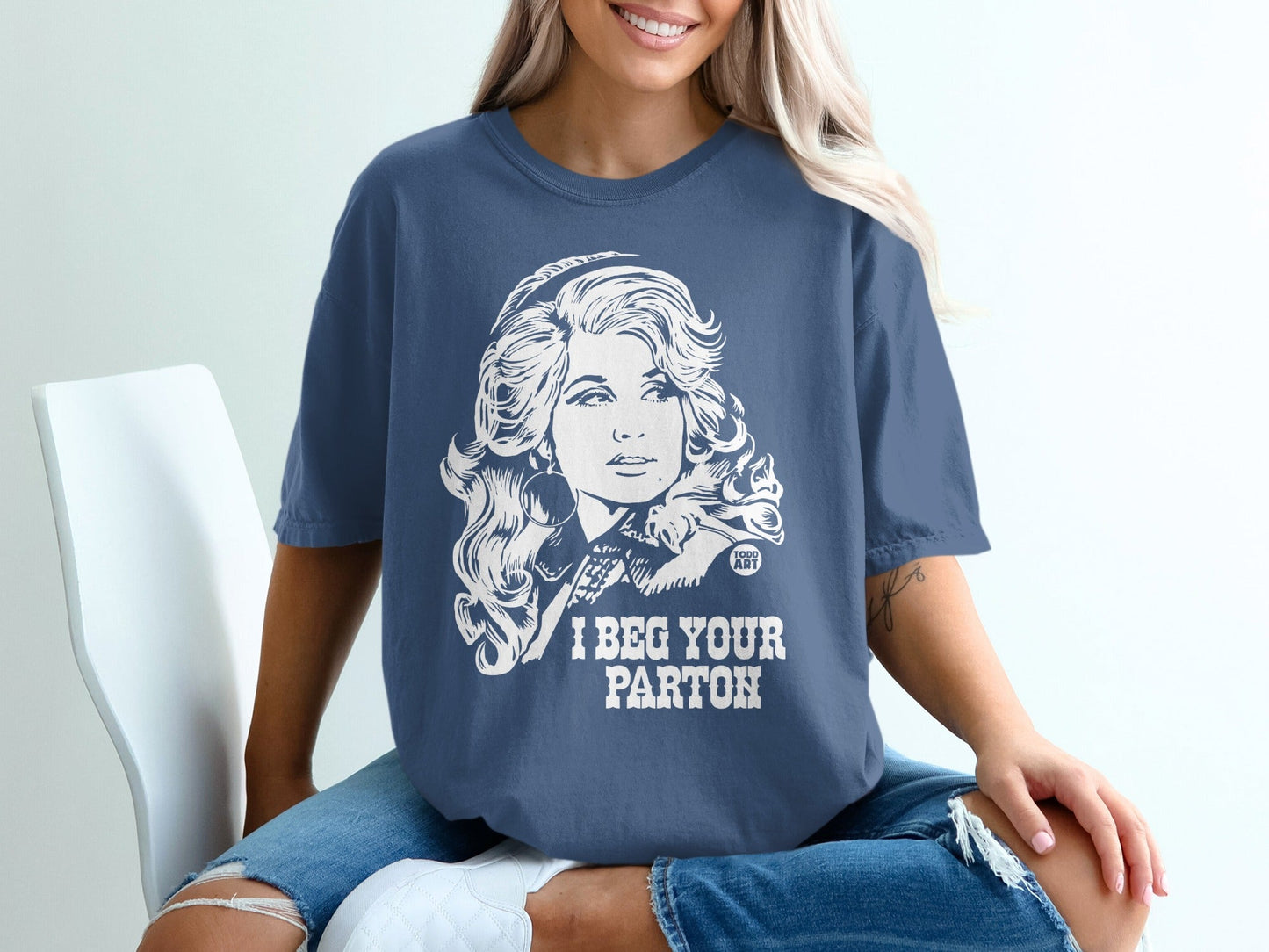 Woman wearing navy t-shirt with Dolly Parton graphic and text "I BEG YOUR PARTON".