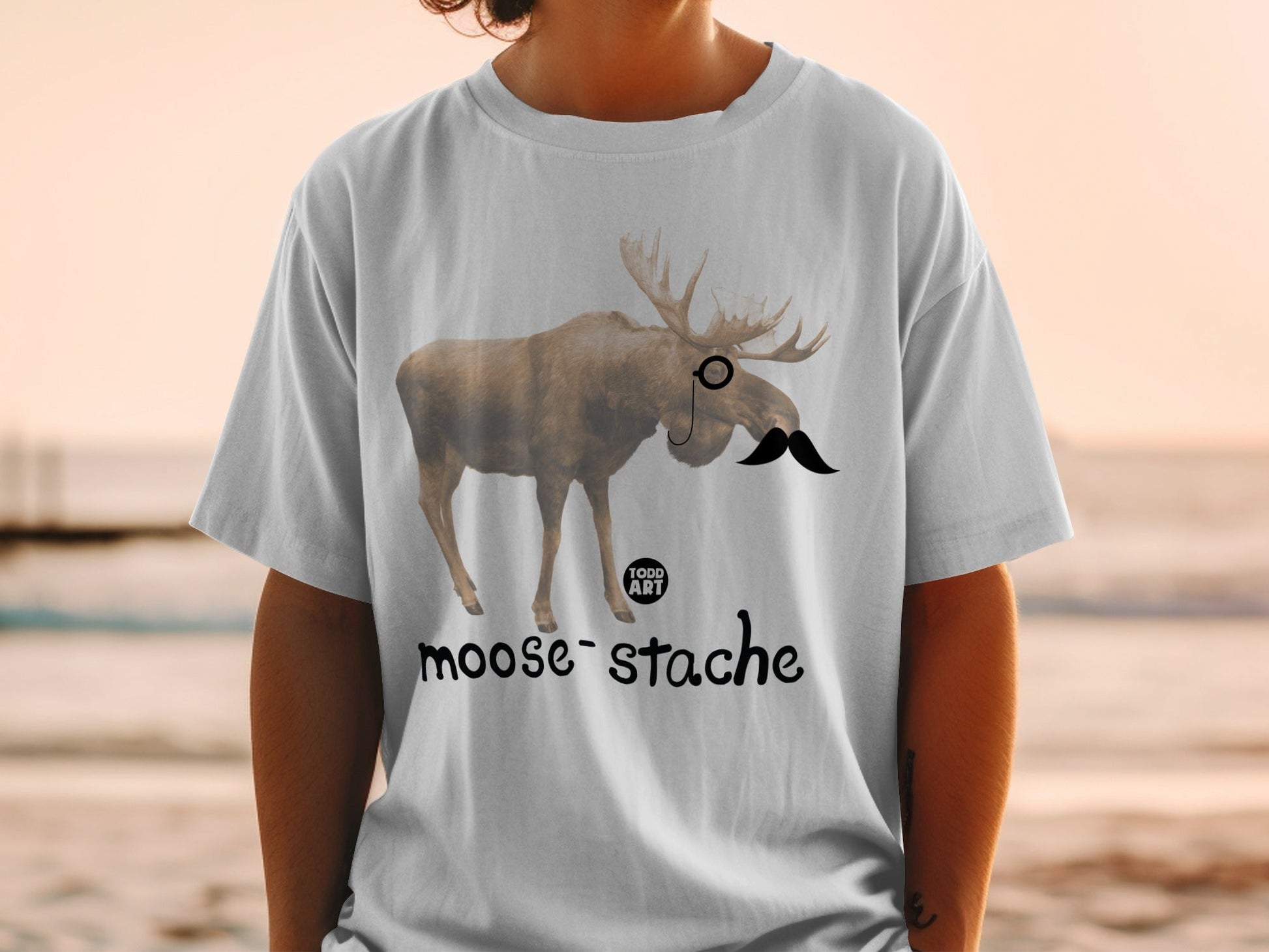 T-shirt with a moose wearing a monocle and mustache, reading "moose-stache".