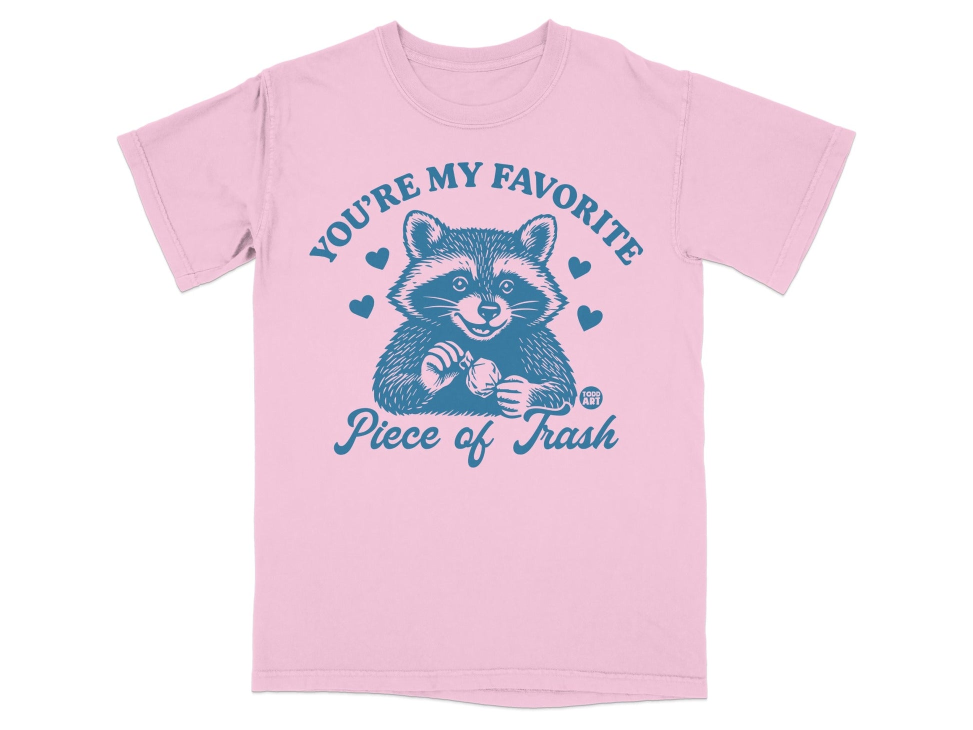 Pink t-shirt with blue graphic of a raccoon and text "YOU'RE MY FAVORITE PIECE OF TRASH".