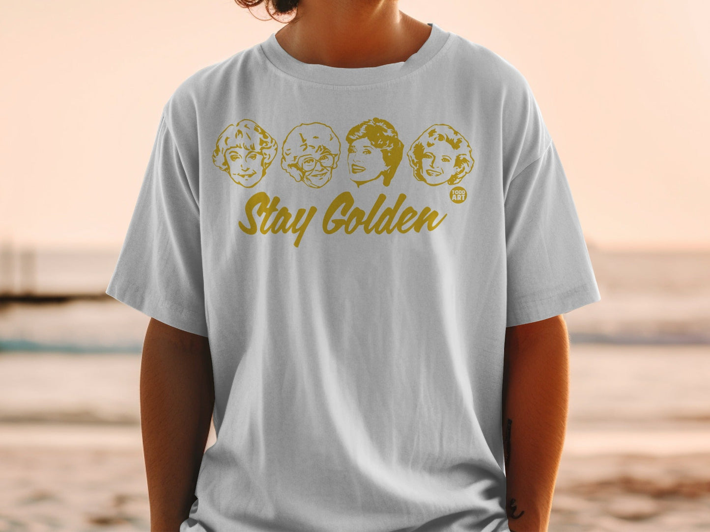 White t-shirt with "Stay Golden" and four cartoon portraits of The Golden Girls.