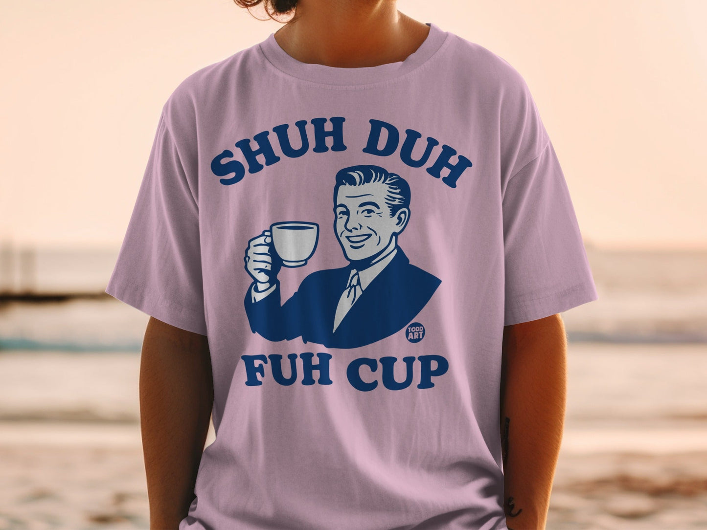 Man in purple t-shirt holding white coffee cup, text reads "SHUH DUH FUH CUP".