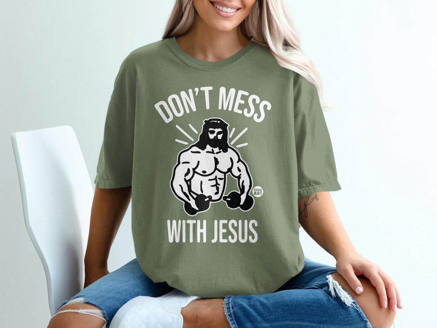 Olive green t-shirt with "Don't Mess With Jesus" and muscular Jesus graphic.
