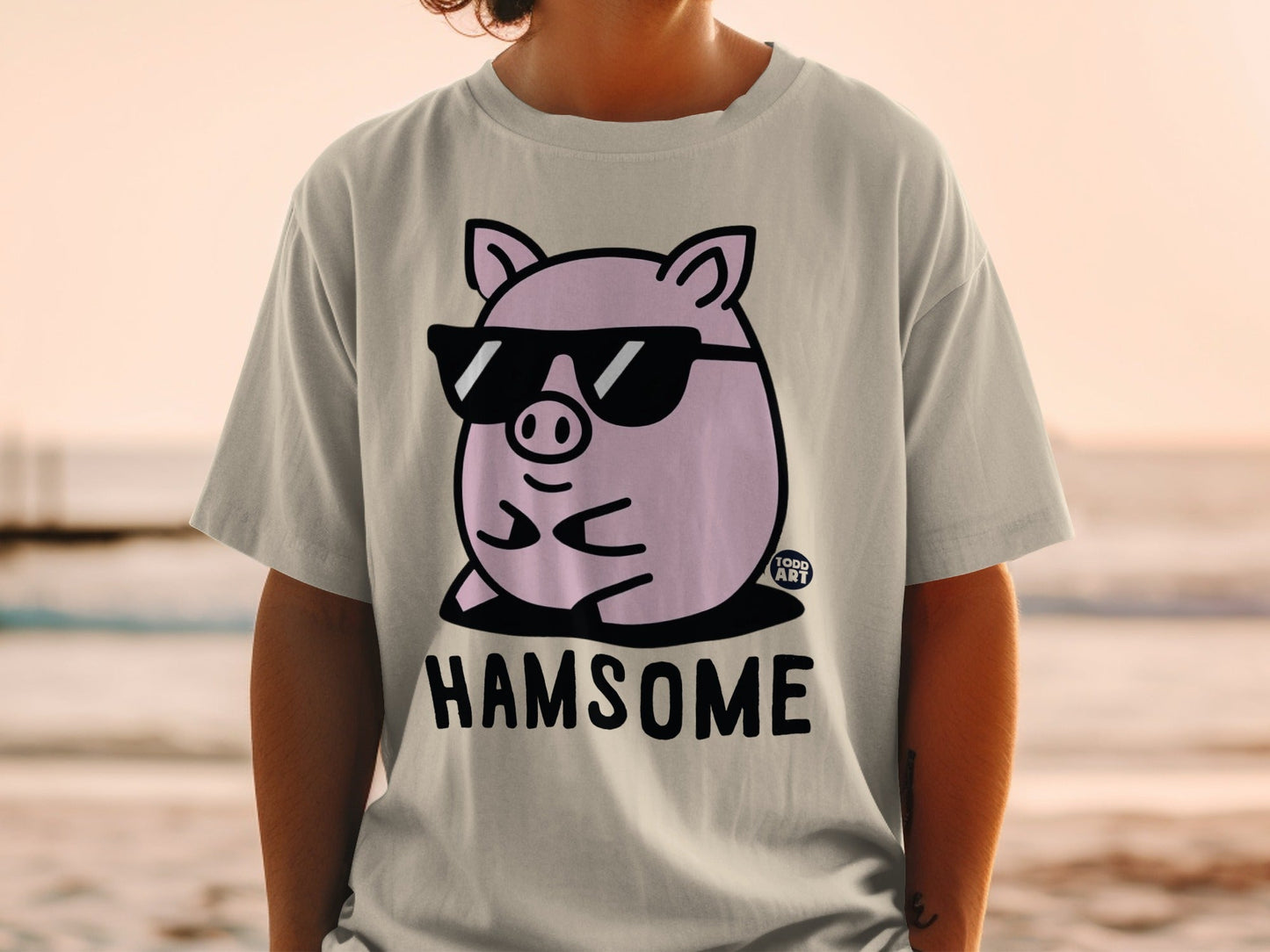 Light grey t-shirt with a cartoon pig wearing sunglasses and the text "HAMSOME".