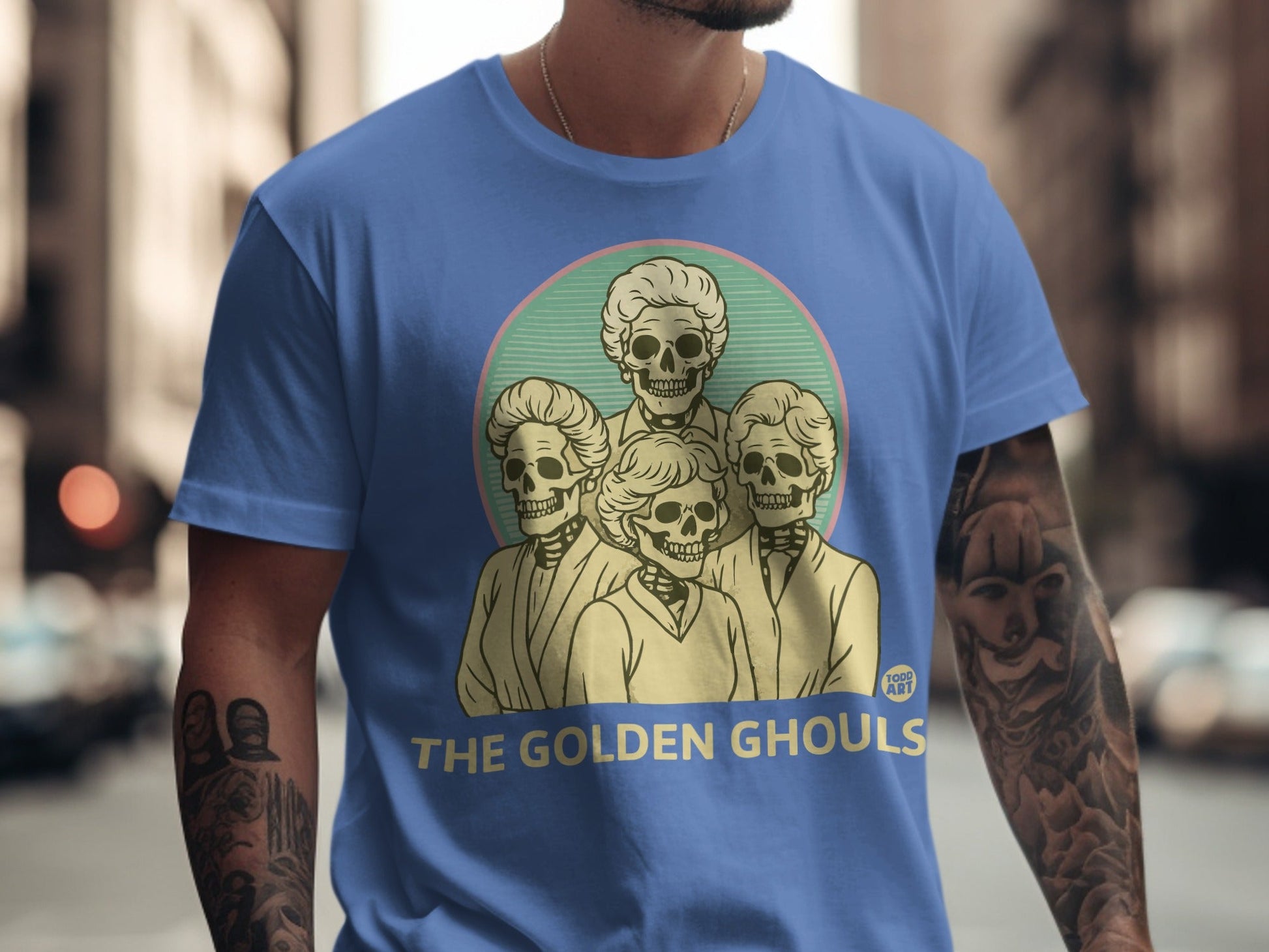 Blue t-shirt with "The Golden Ghouls" text and a circular graphic of skeleton women.