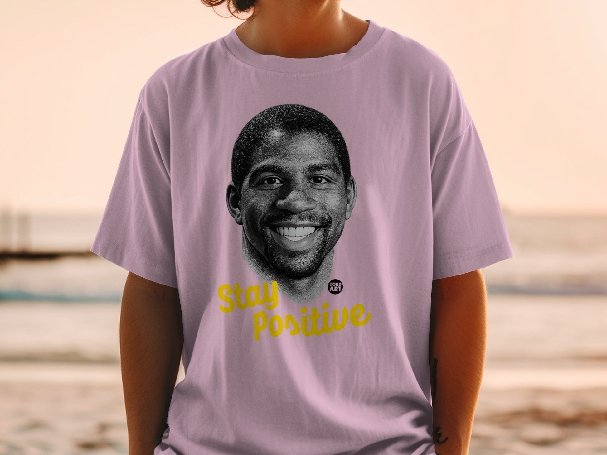 Magic Johnson portrait on a lilac t-shirt with "Stay Positive" text.