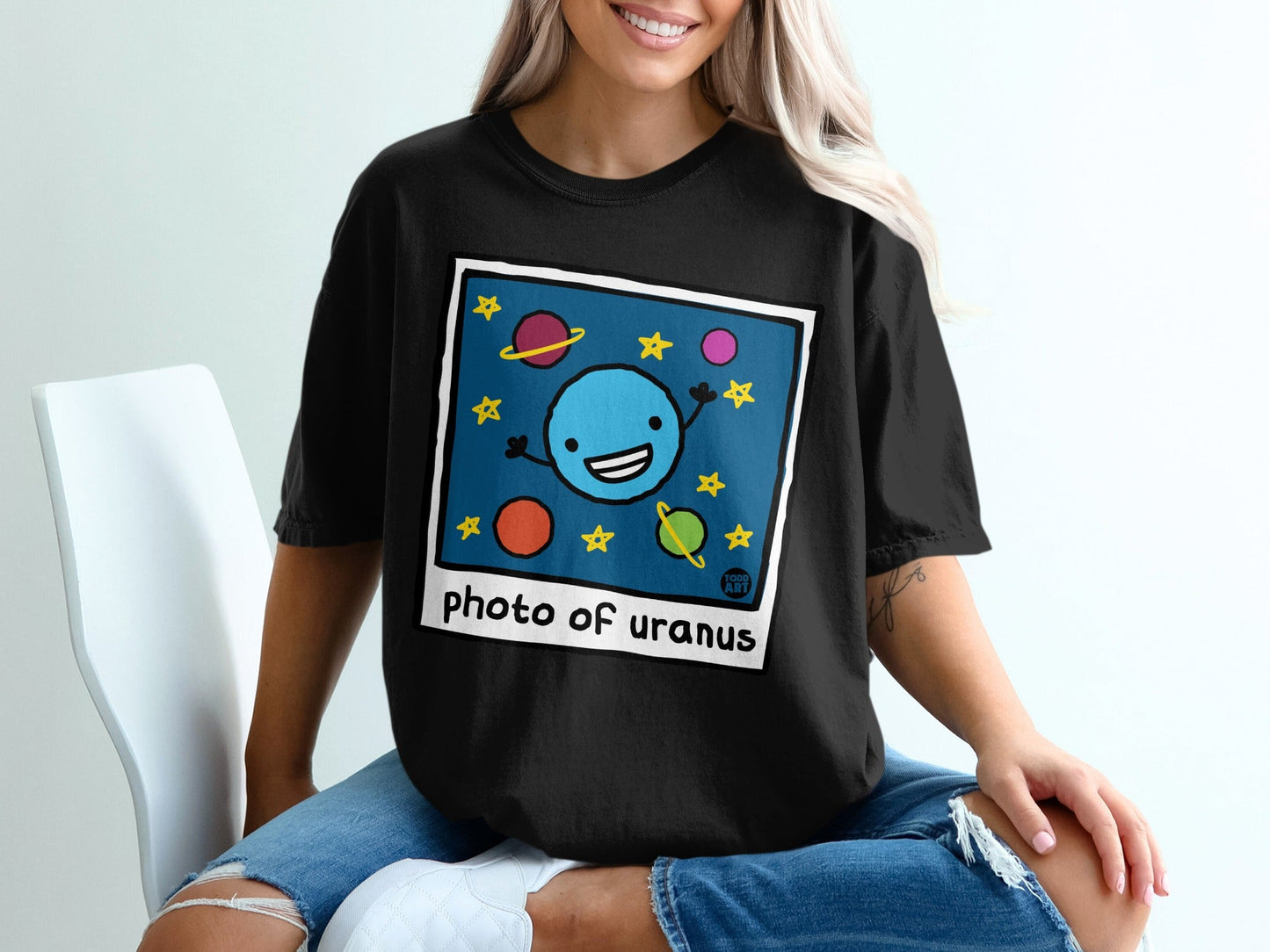 Black t-shirt featuring a cartoon drawing of smiling planet Uranus with stars and planets.