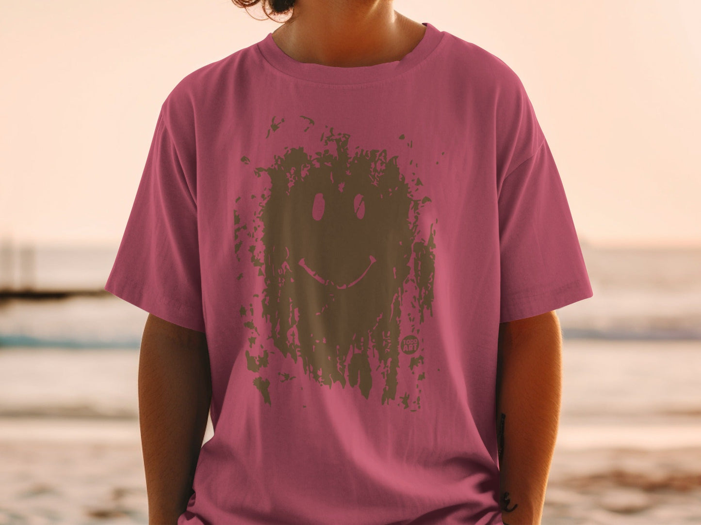 Pink t-shirt with distressed smiley face graphic on a person.