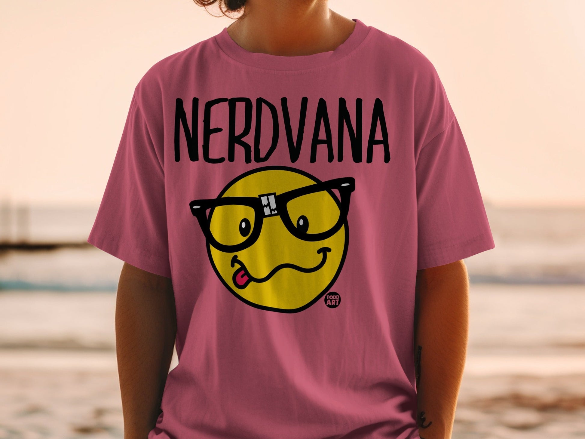 Pink t-shirt with "NERDVANA" text and a yellow smiley face wearing glasses.
