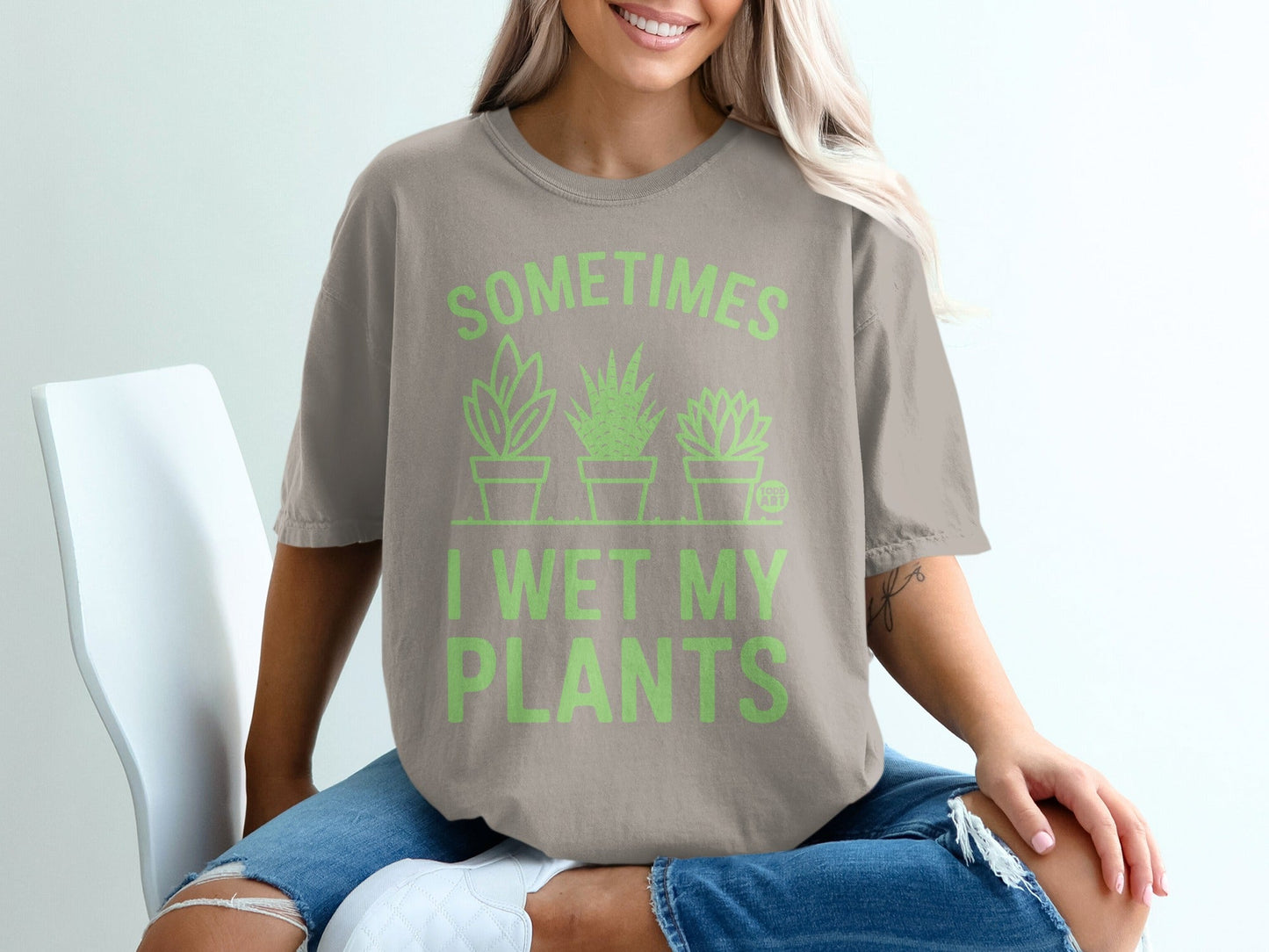 Woman wearing tan t-shirt with "SOMETIMES I WET MY PLANTS" text and plant graphics.
