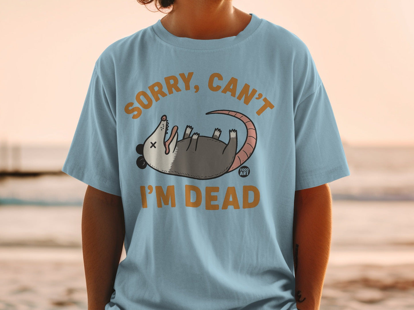 Light blue t-shirt with opossum graphic and text "SORRY, CAN'T I'M DEAD".