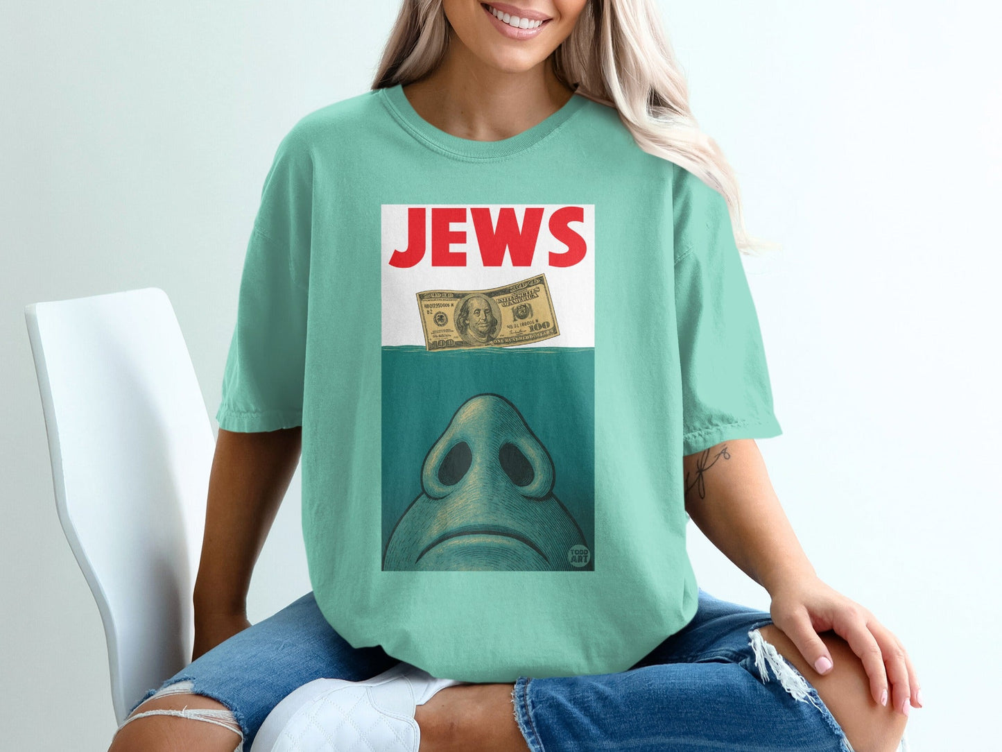 T-shirt with "JEWS" text and dollar bill submerged in water.