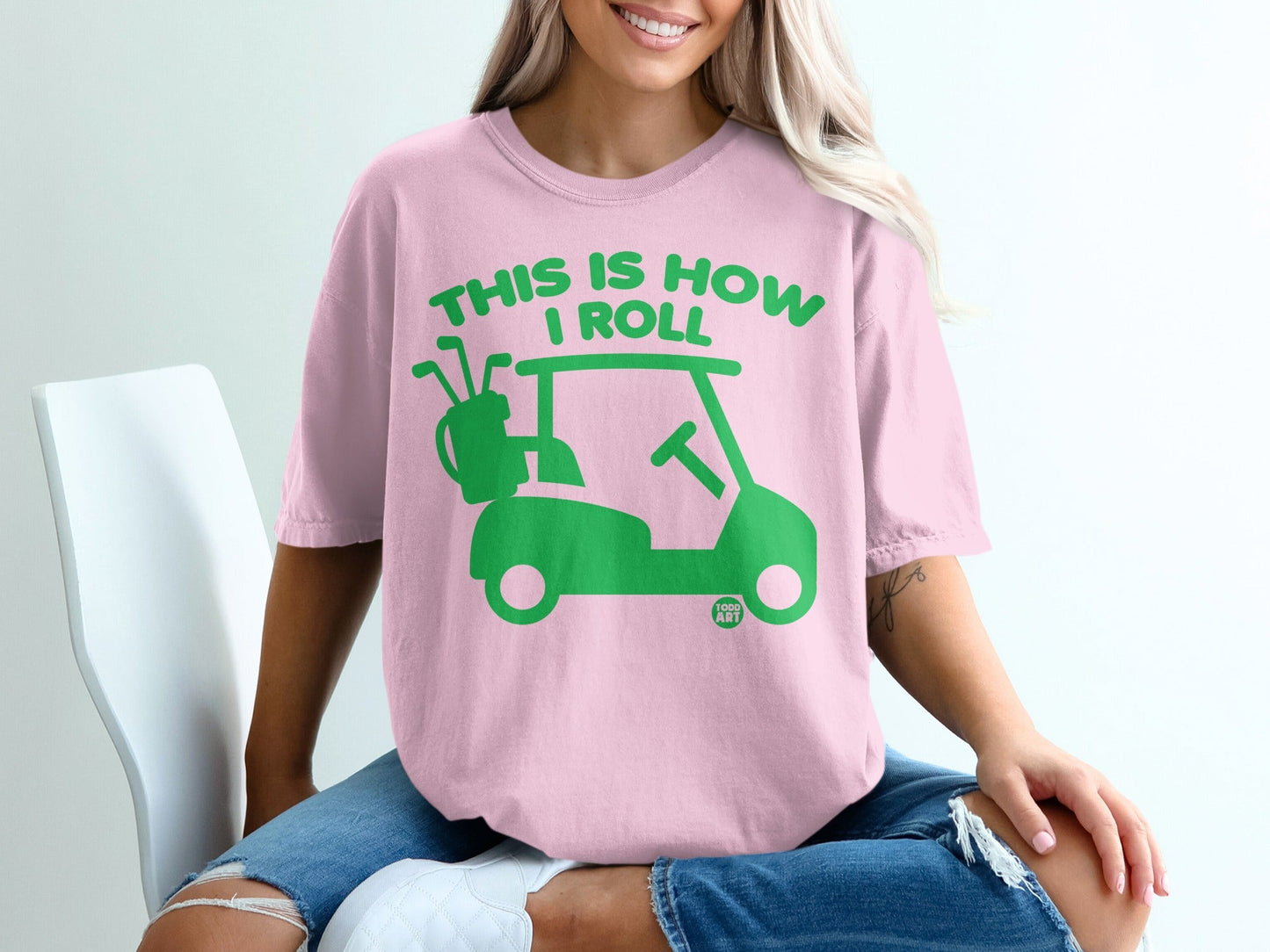 Pink t-shirt with green text and graphics: "THIS IS HOW I ROLL" and a golf cart.