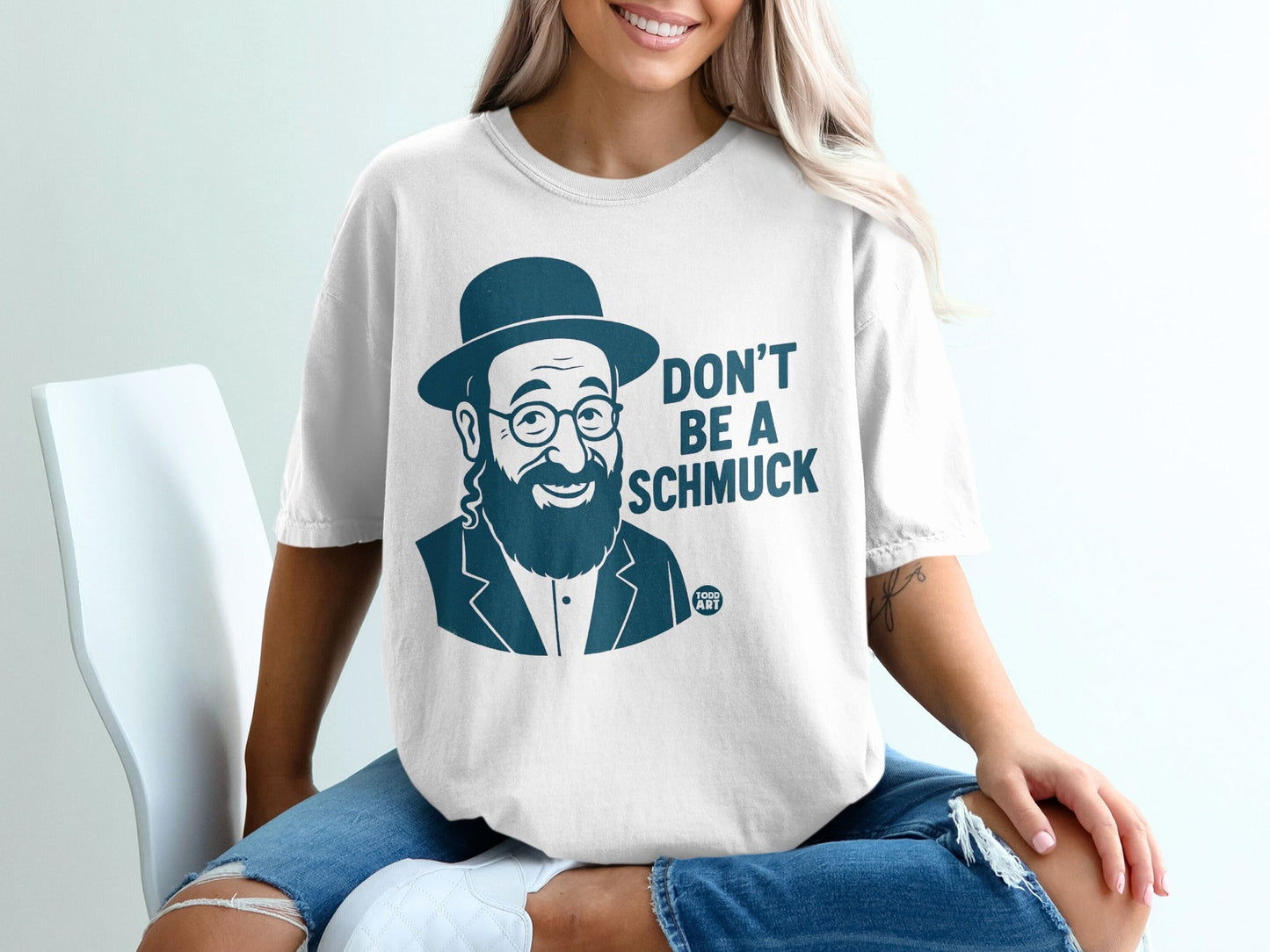 White t-shirt with a man in a hat and glasses, text reads "DON'T BE A SCHMUCK".