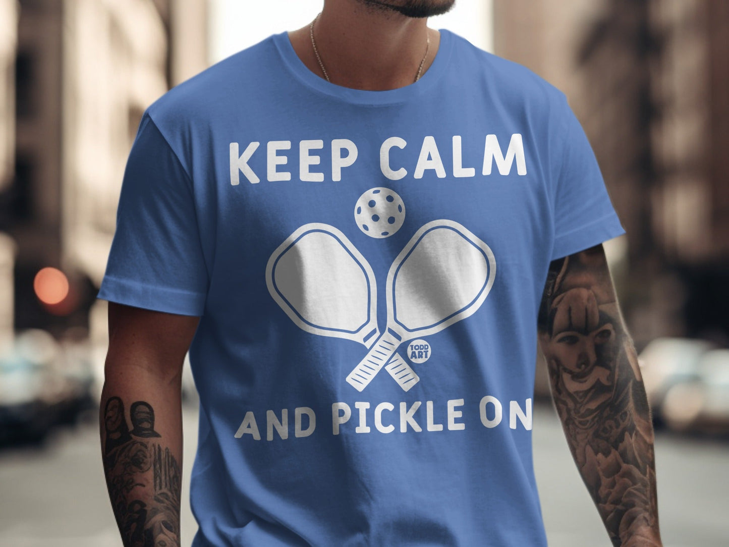 Blue t-shirt with "Keep Calm and Pickle On" and crossed pickleball paddles.