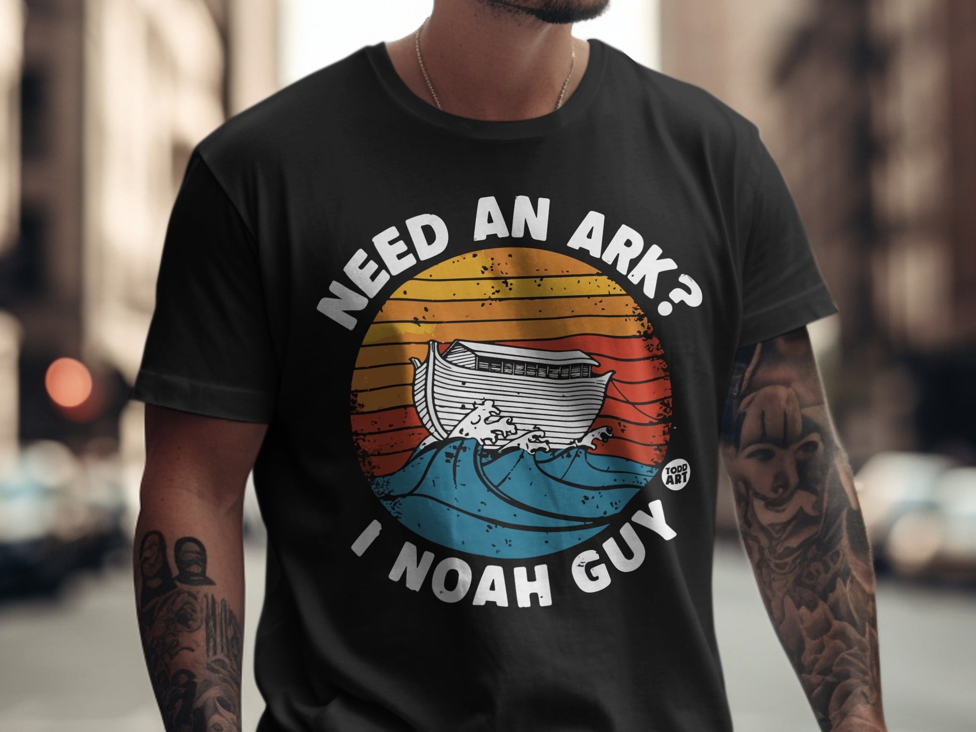Black t-shirt with "Need an Ark? I Noah Guy" and a stylized ark on waves.