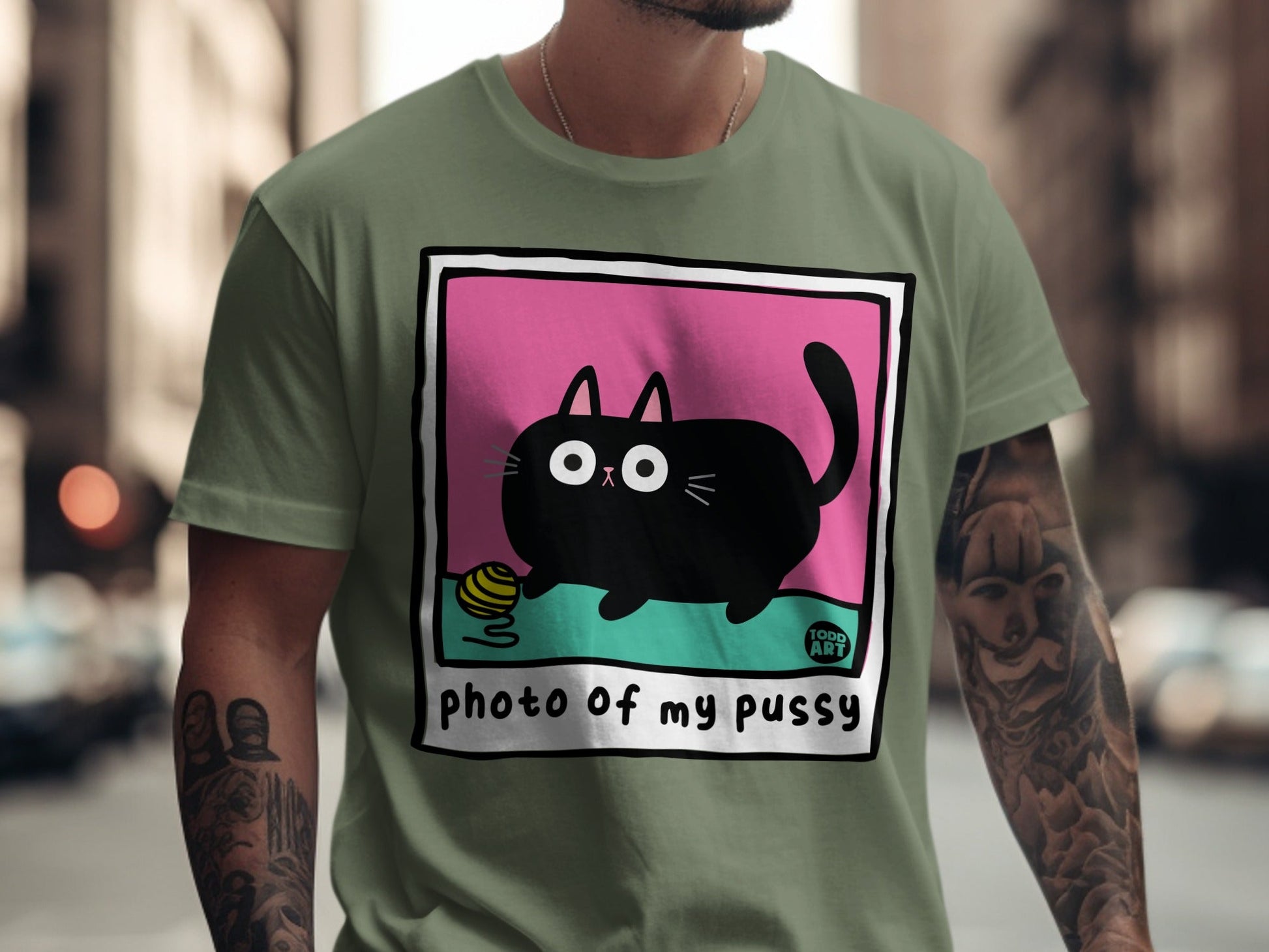 Black cartoon cat with yarn ball on green t-shirt with "photo of my pussy" text.