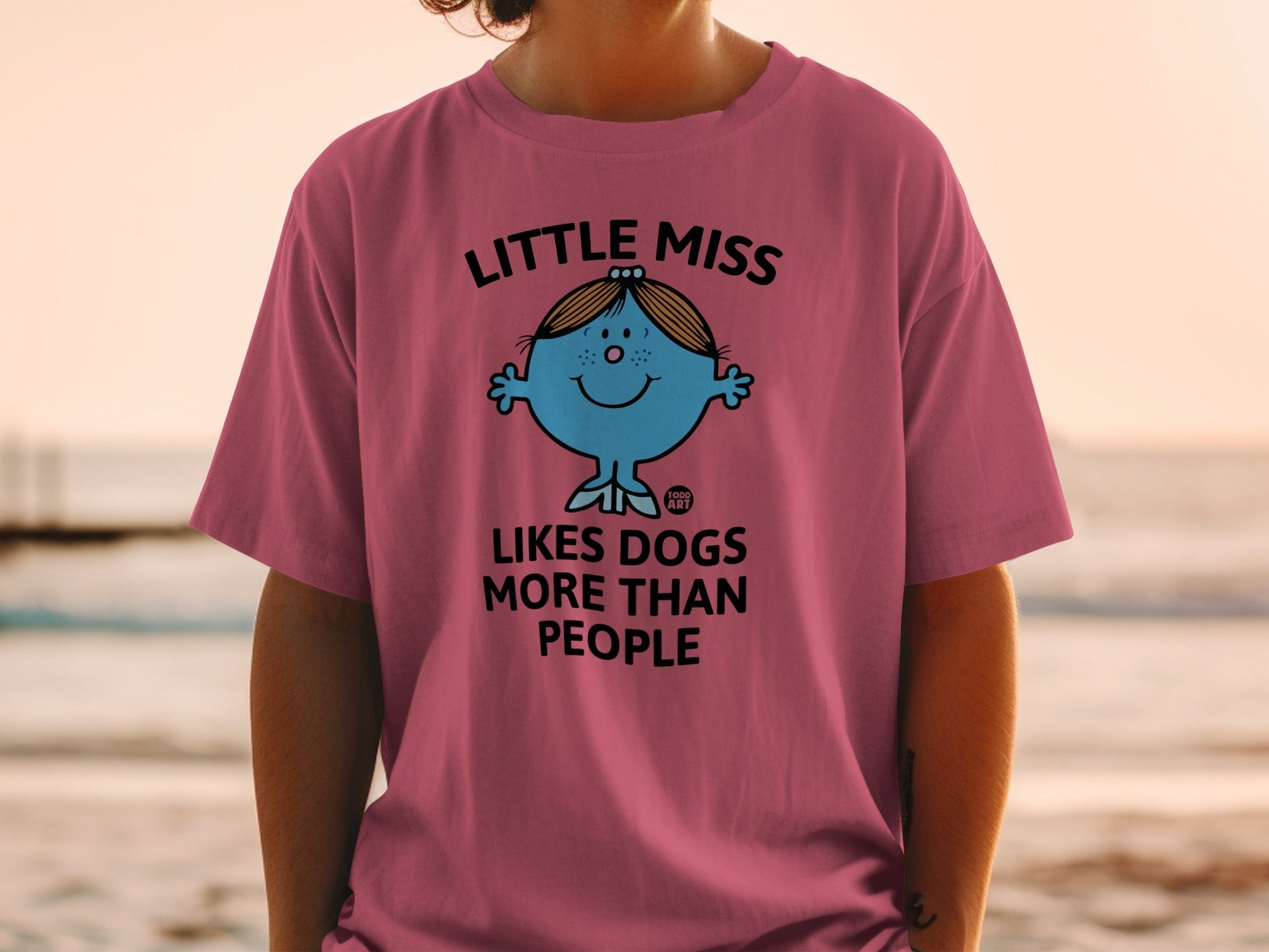 Little Miss character with "Likes Dogs More Than People" text on a pink t-shirt.