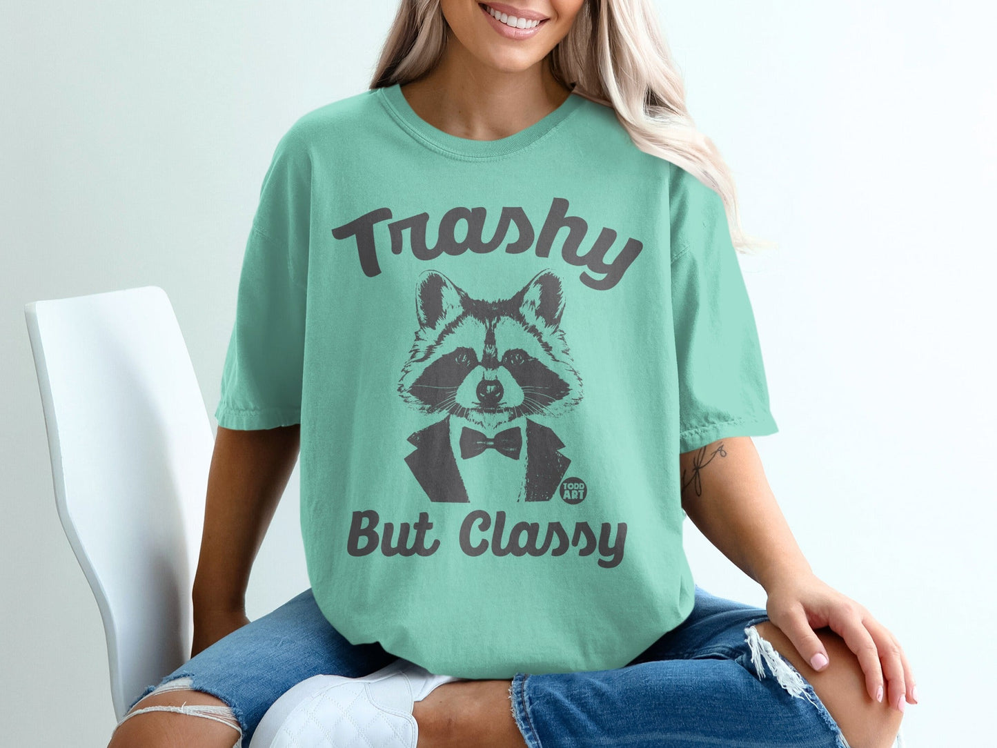 Raccoon wearing a tuxedo, "Trashy But Classy" text on a light teal t-shirt.