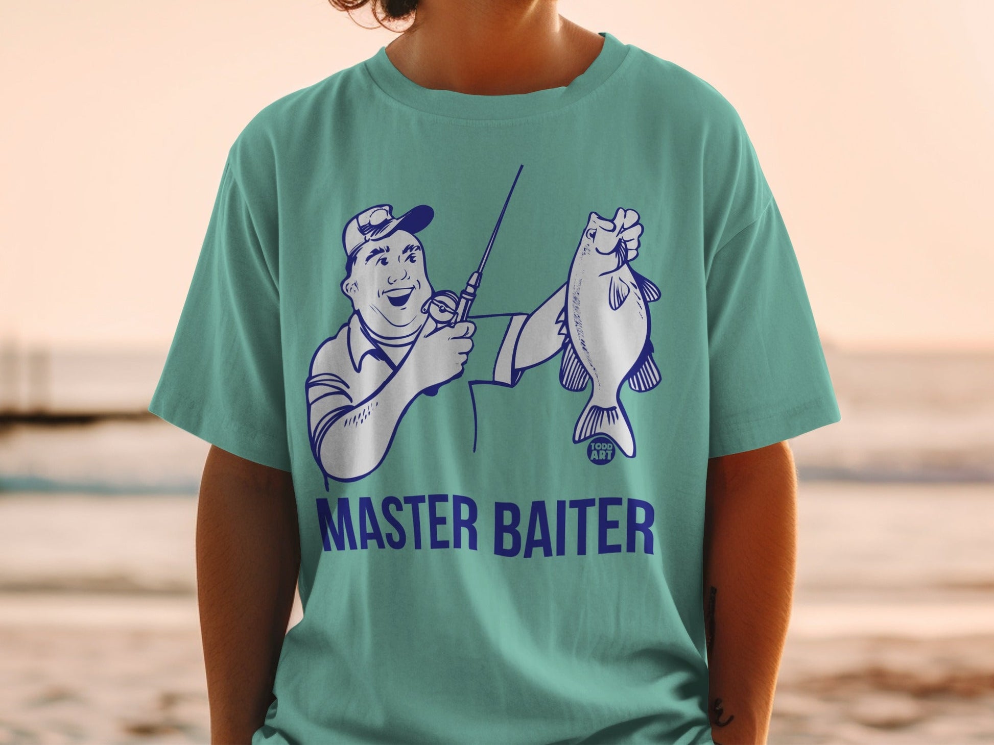 Teal t-shirt with cartoon fisherman holding a fish, text "MASTER BAITER".