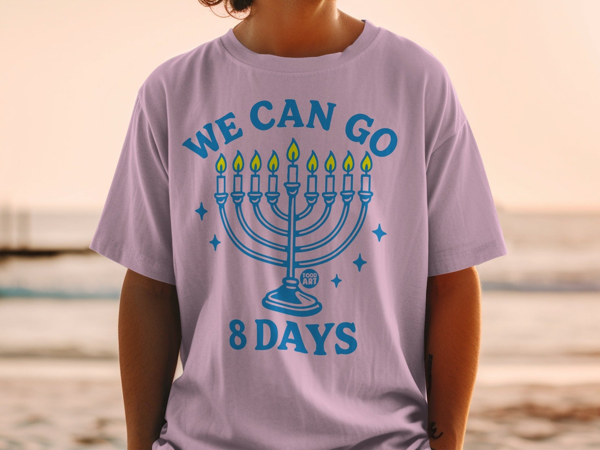 Purple t-shirt with blue text "WE CAN GO 8 DAYS" and a menorah.