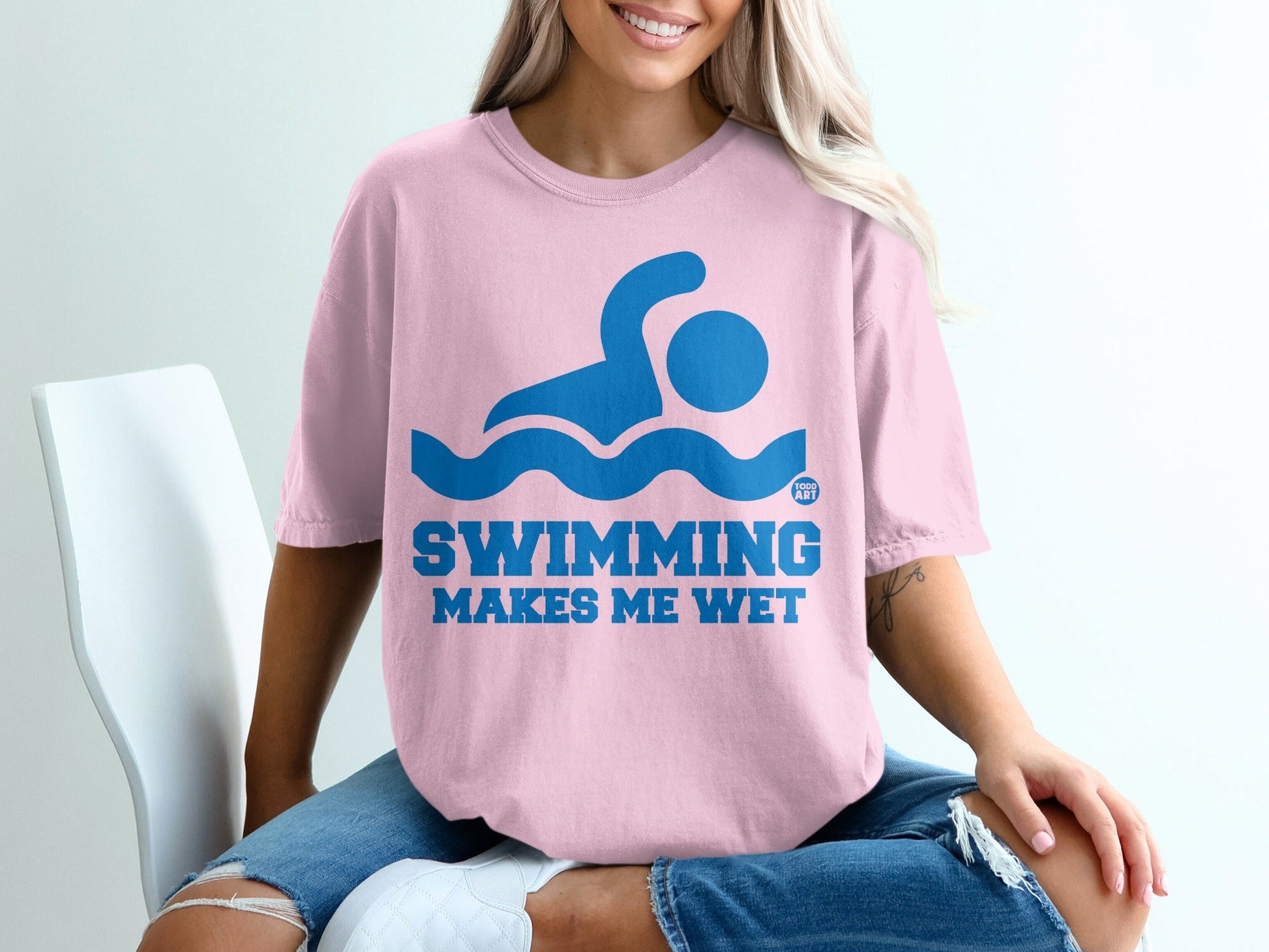 Pink t-shirt with blue swimming graphic and "SWIMMING MAKES ME WET" text.