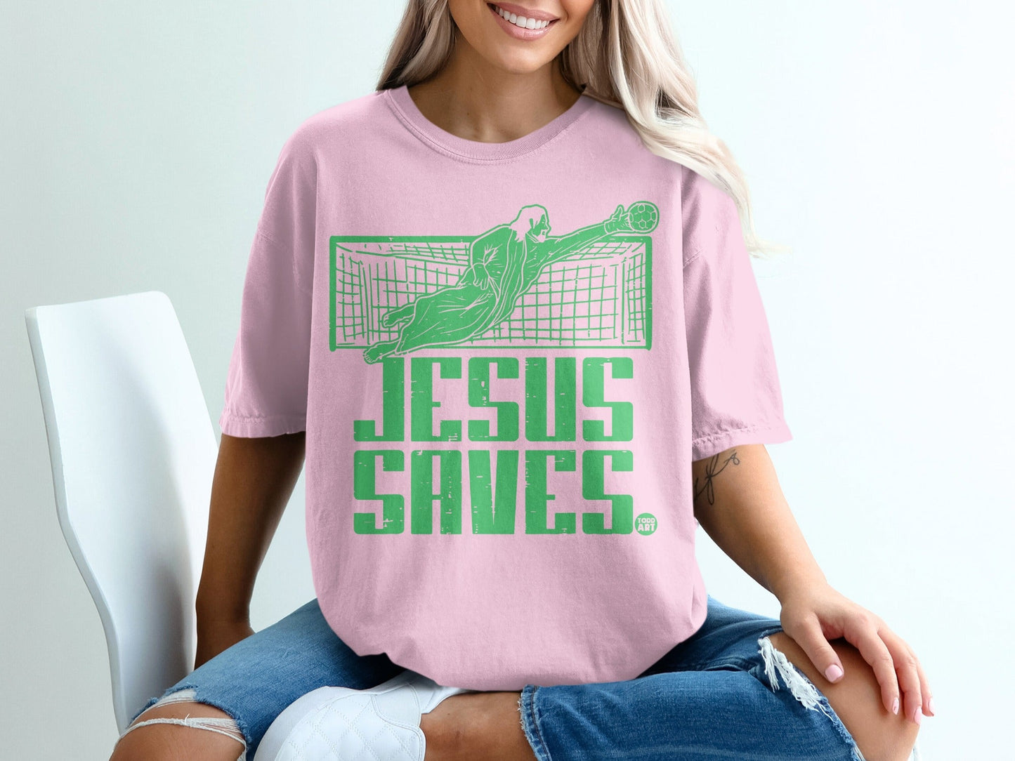 Pink t-shirt with "Jesus Saves" text and a goalkeeper catching a soccer ball.