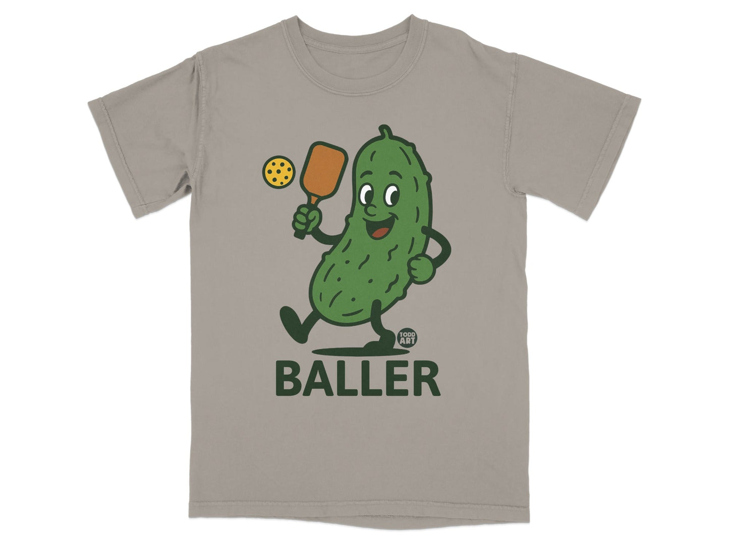 Cartoon pickle character playing tennis on a t-shirt with "BALLER" text.