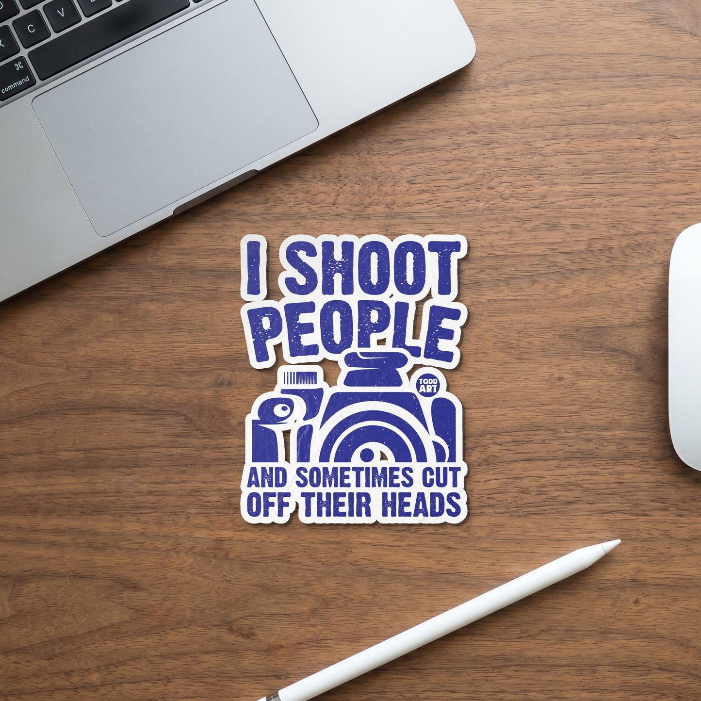 Blue sticker with text "I shoot people and sometimes cut off their heads" and a camera graphic.