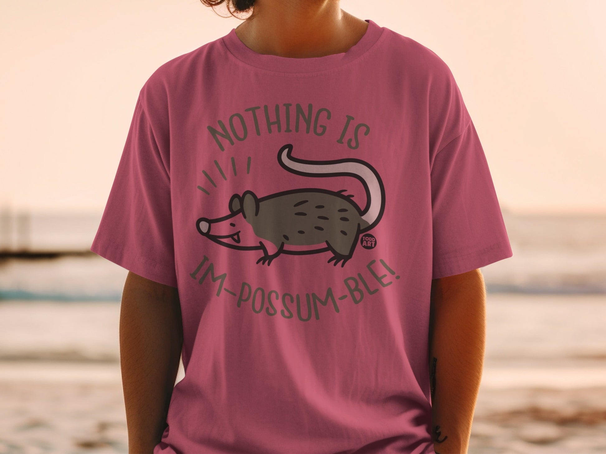 Pink t-shirt with possum graphic and text "Nothing is im-possum-ble!"