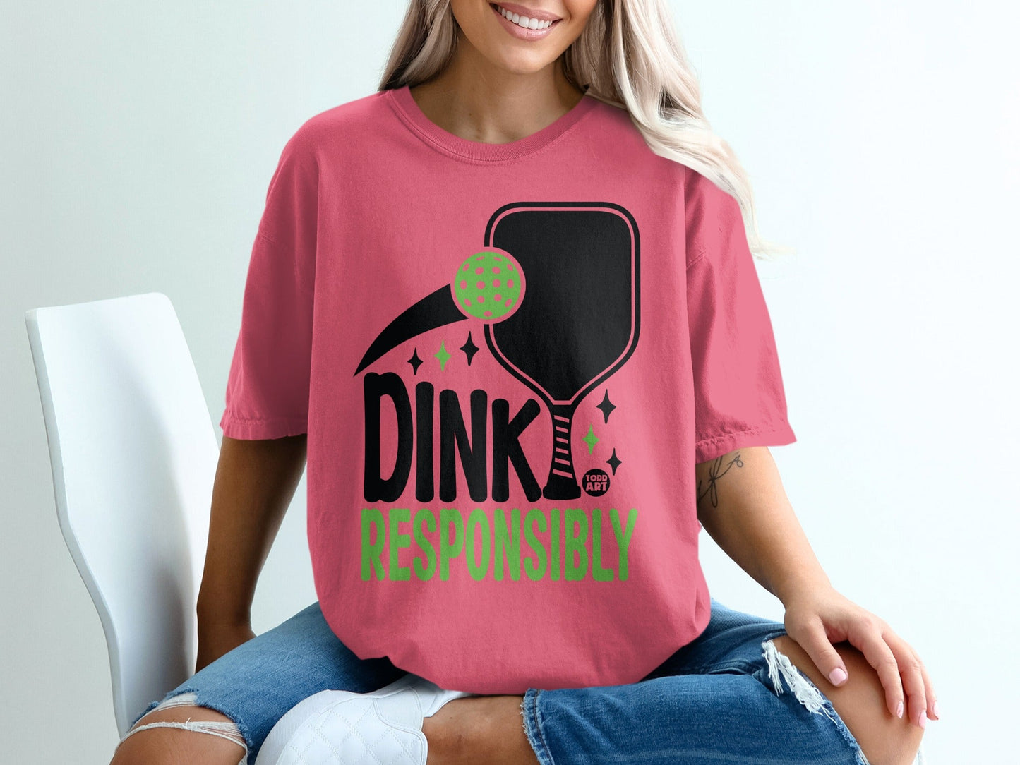 Pink t-shirt with pickleball paddle, ball, and "DINK RESPONSIBLY" text.