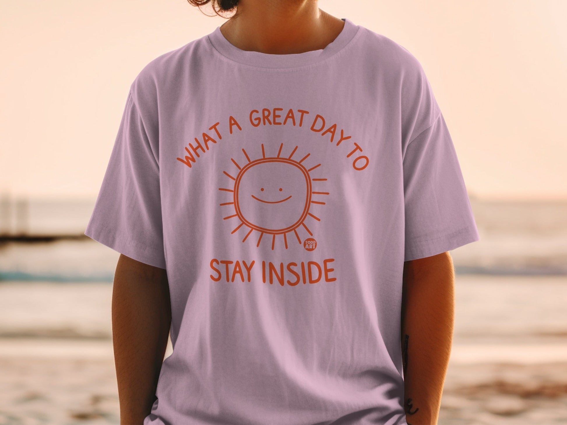 Purple t-shirt with orange sun graphic and text "WHAT A GREAT DAY TO STAY INSIDE."