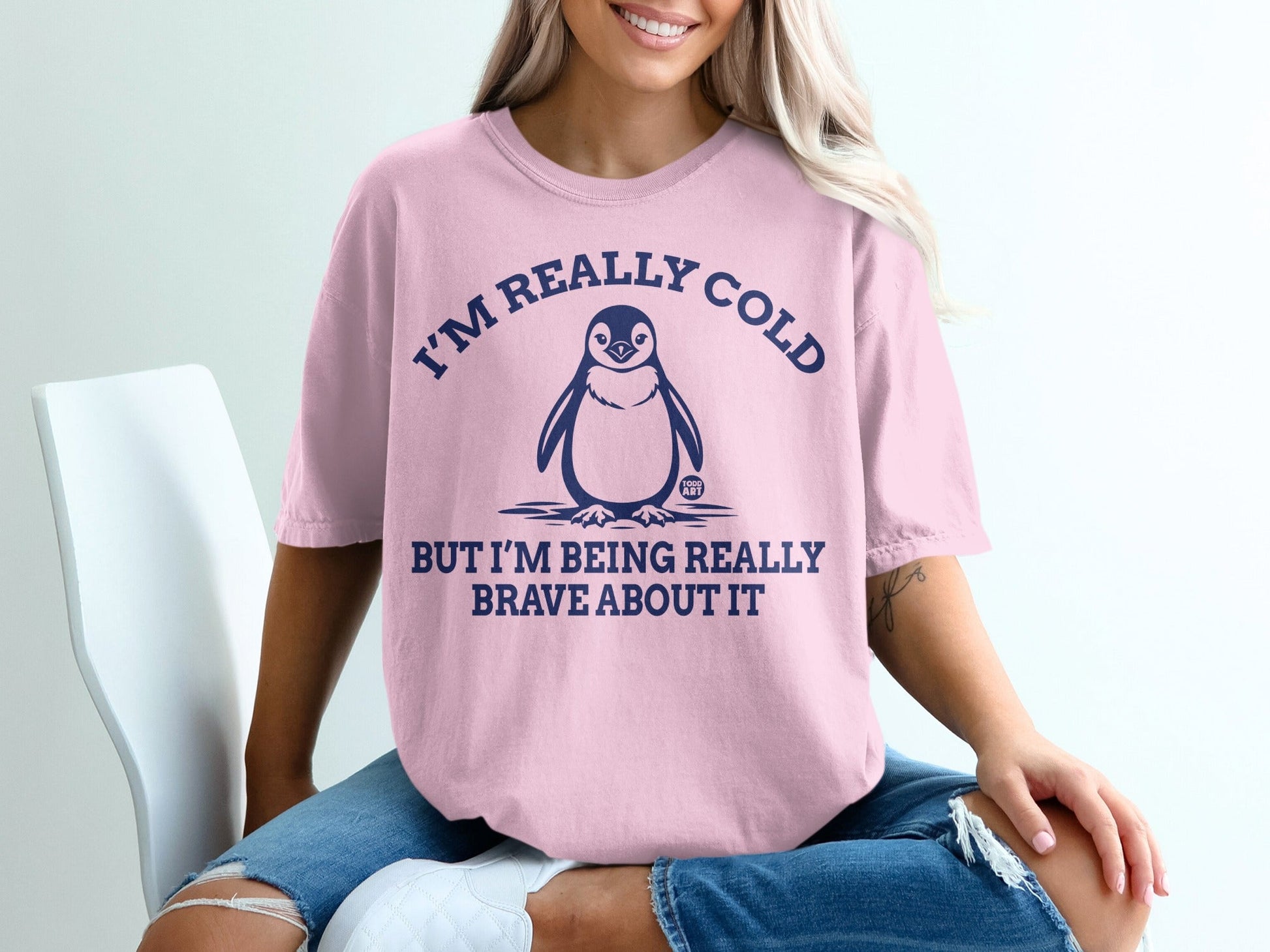 Pink t-shirt with penguin graphic and text "I'm really cold but I'm being really brave about it."