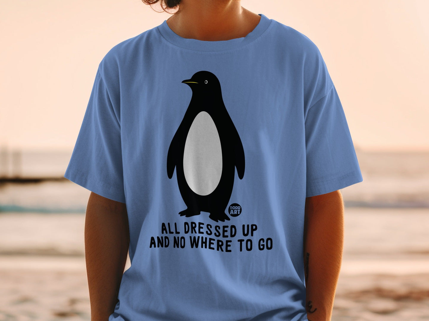 Blue t-shirt with a penguin illustration and "ALL DRESSED UP AND NO WHERE TO GO" text.