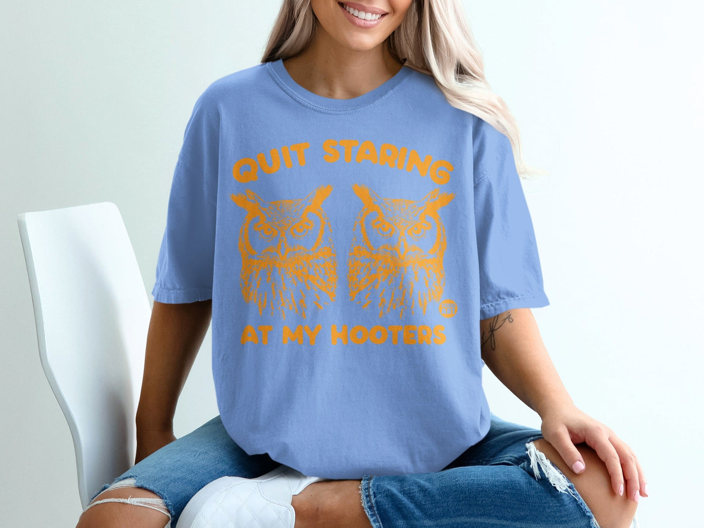 Blue t-shirt with orange text and owl graphics that reads "QUIT STARING AT MY HOOTERS".