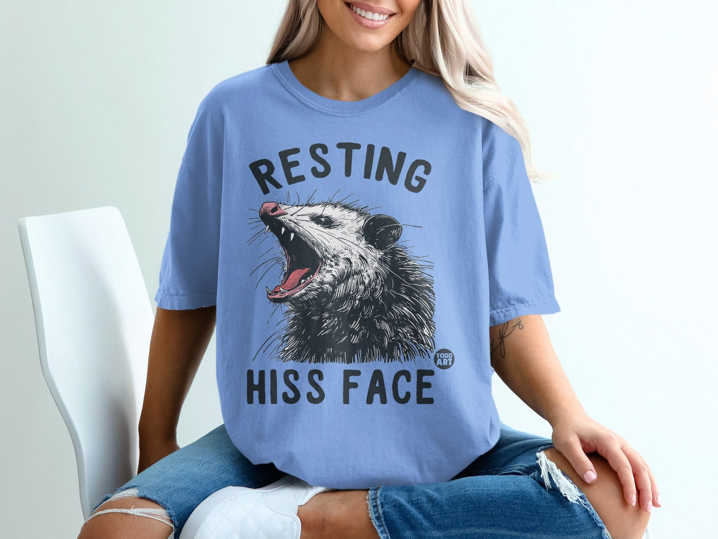 Blue t-shirt with opossum and text "RESTING HISS FACE".