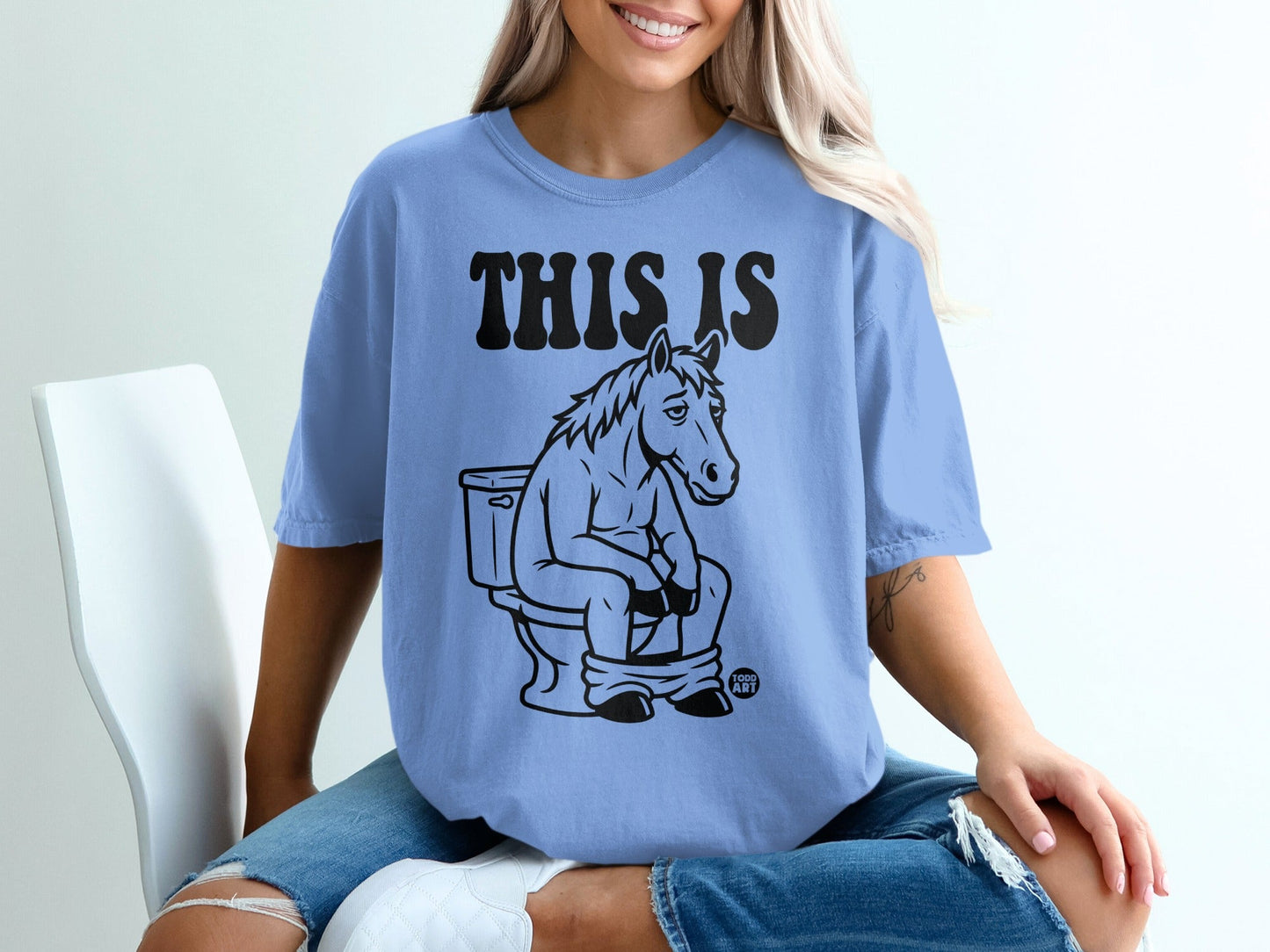 Light blue t-shirt with black text and graphic of a horse on a toilet.