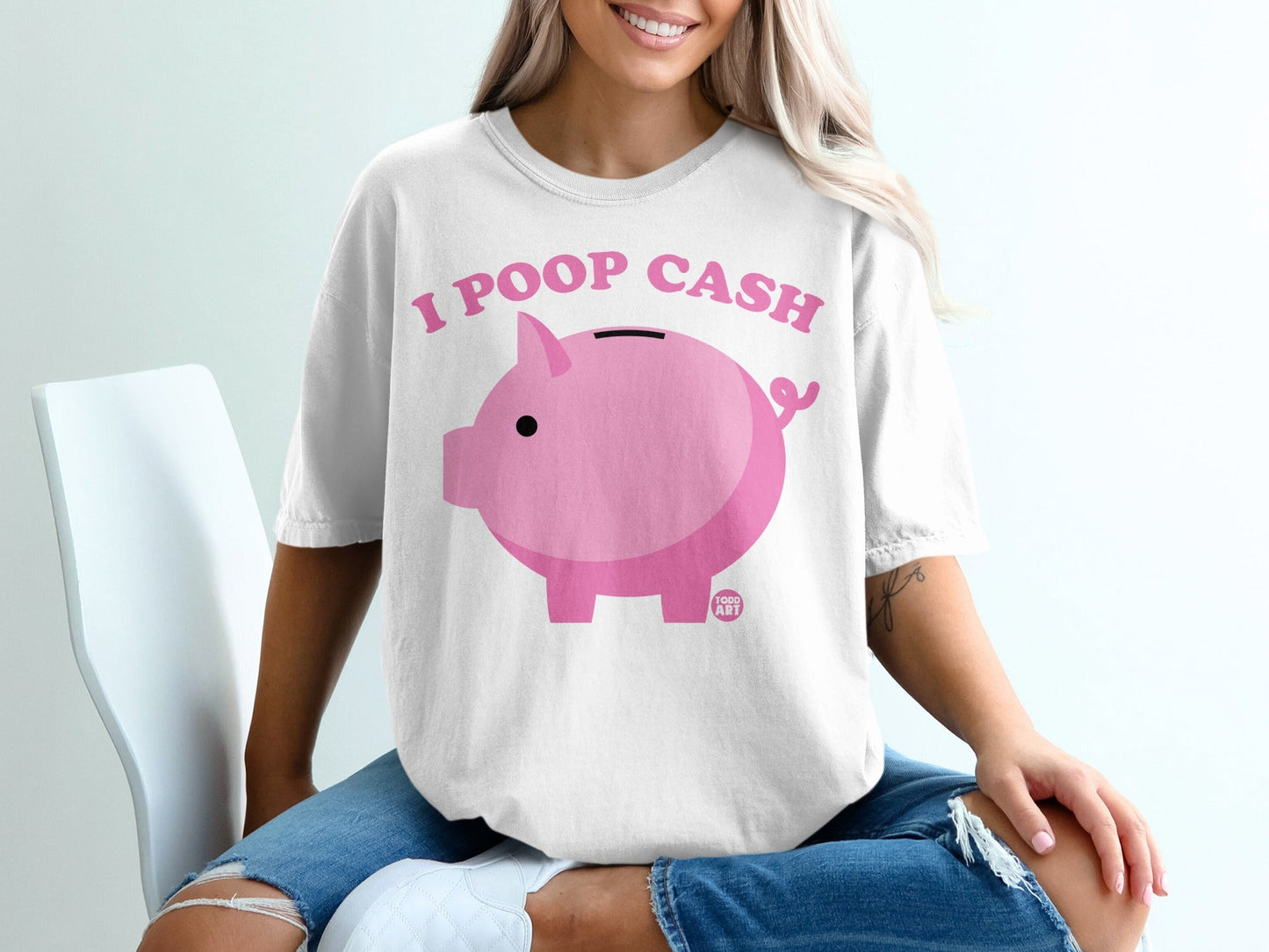White t-shirt with pink piggy bank and text "I POOP CASH".
