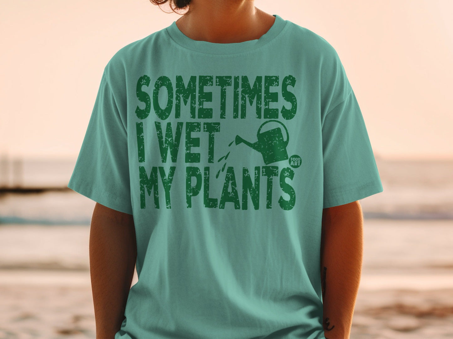 Green t-shirt with "Sometimes I Wet My Plants" text and watering can graphic.