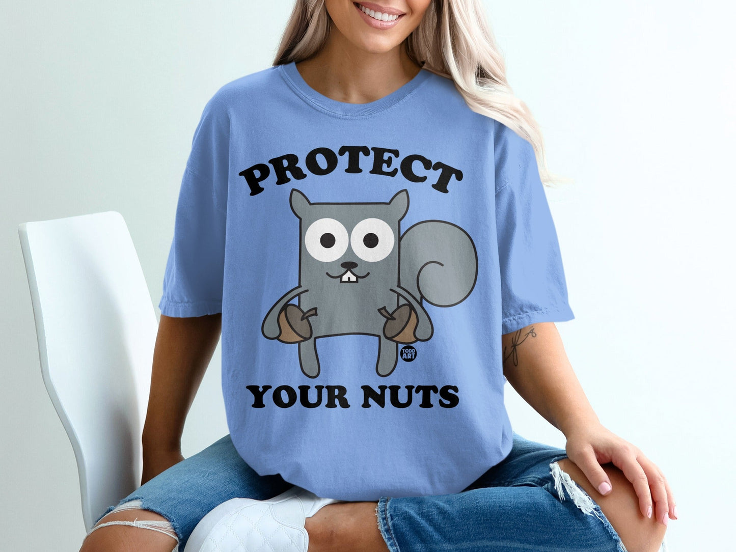 Blue t-shirt with cartoon squirrel holding acorns, text "PROTECT YOUR NUTS".