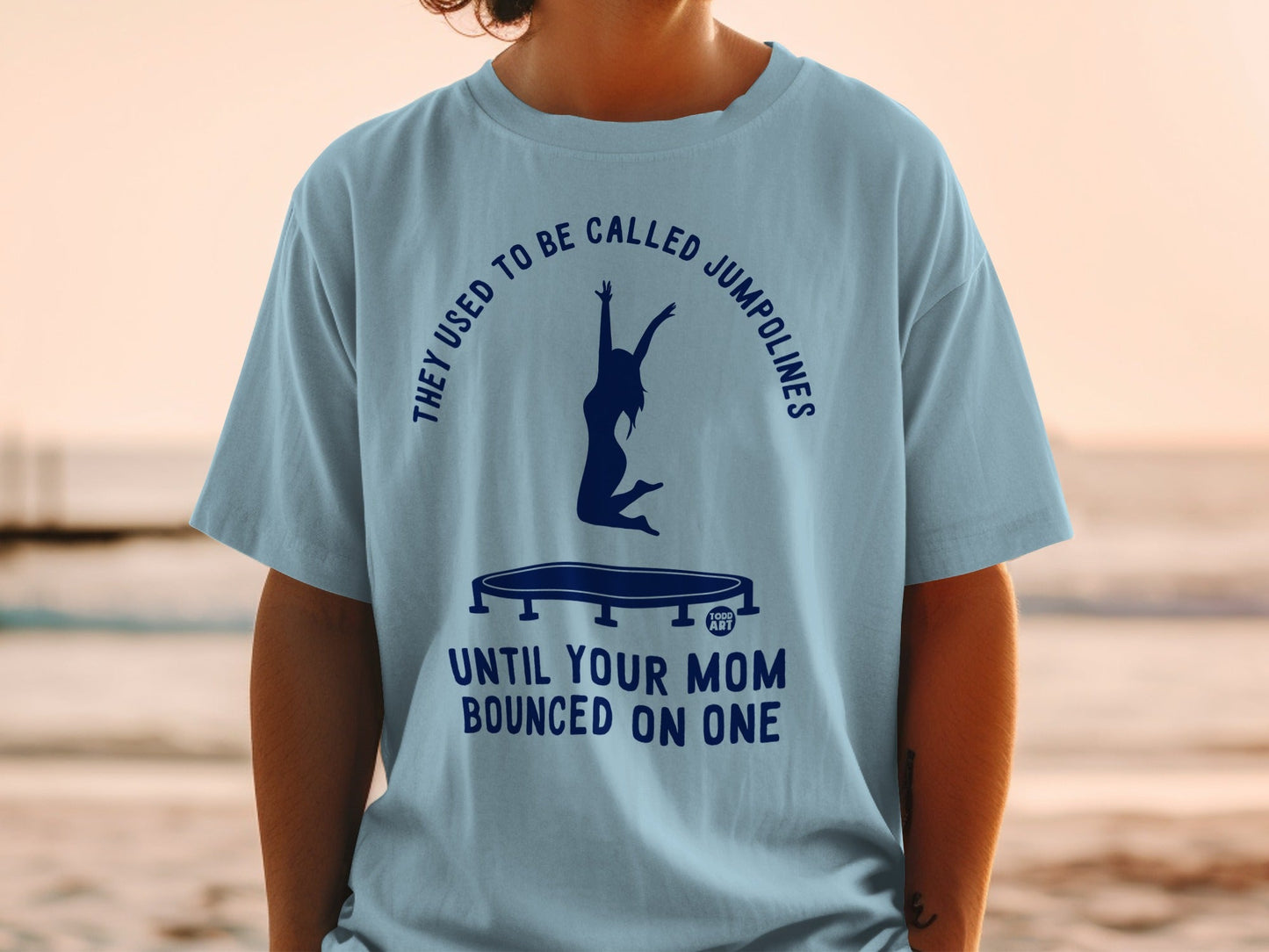 Light blue t-shirt with graphic of a person jumping on a trampoline and text.