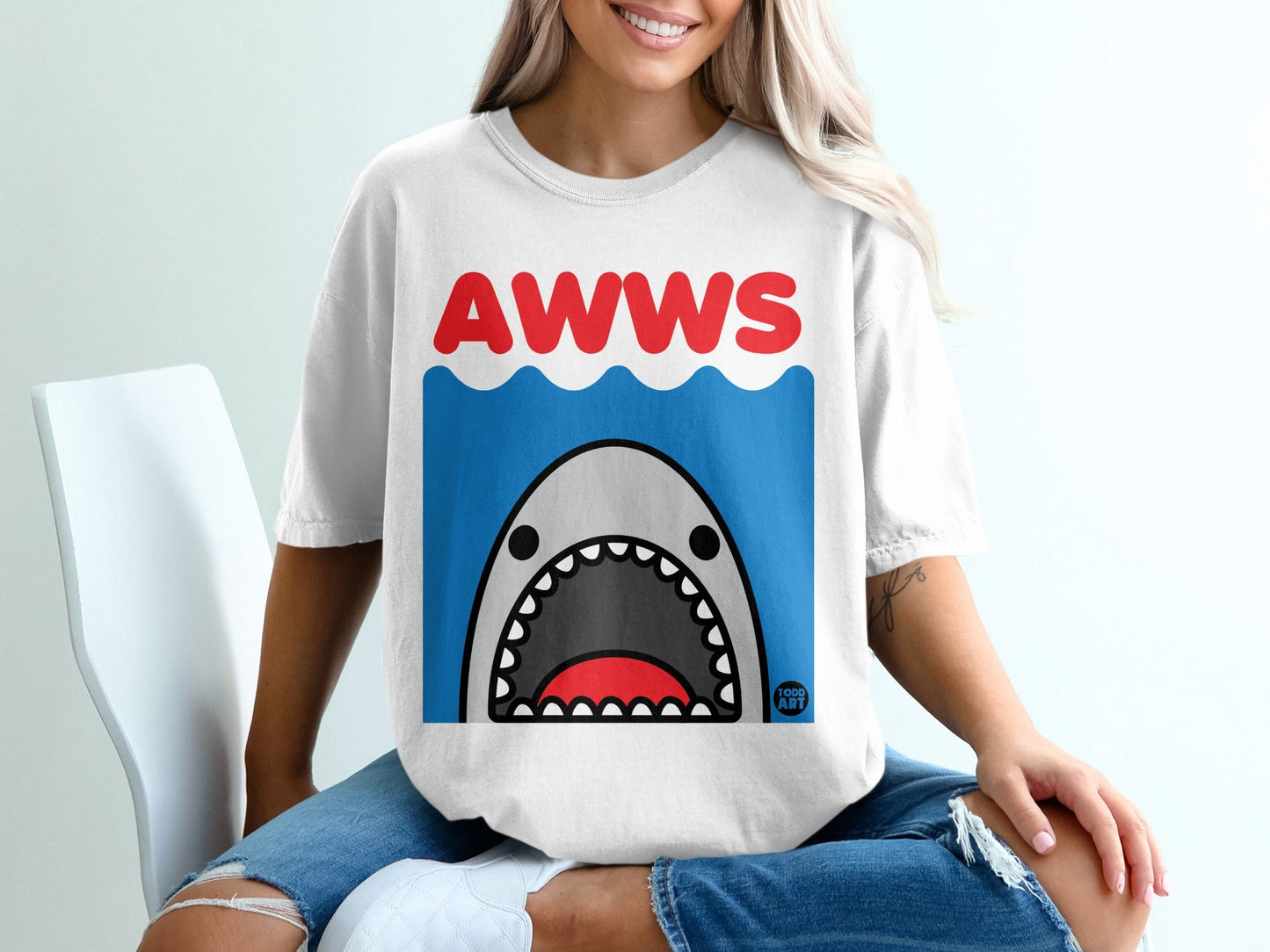 T-shirt with cartoon shark and "AWWS" text on wavy blue background.